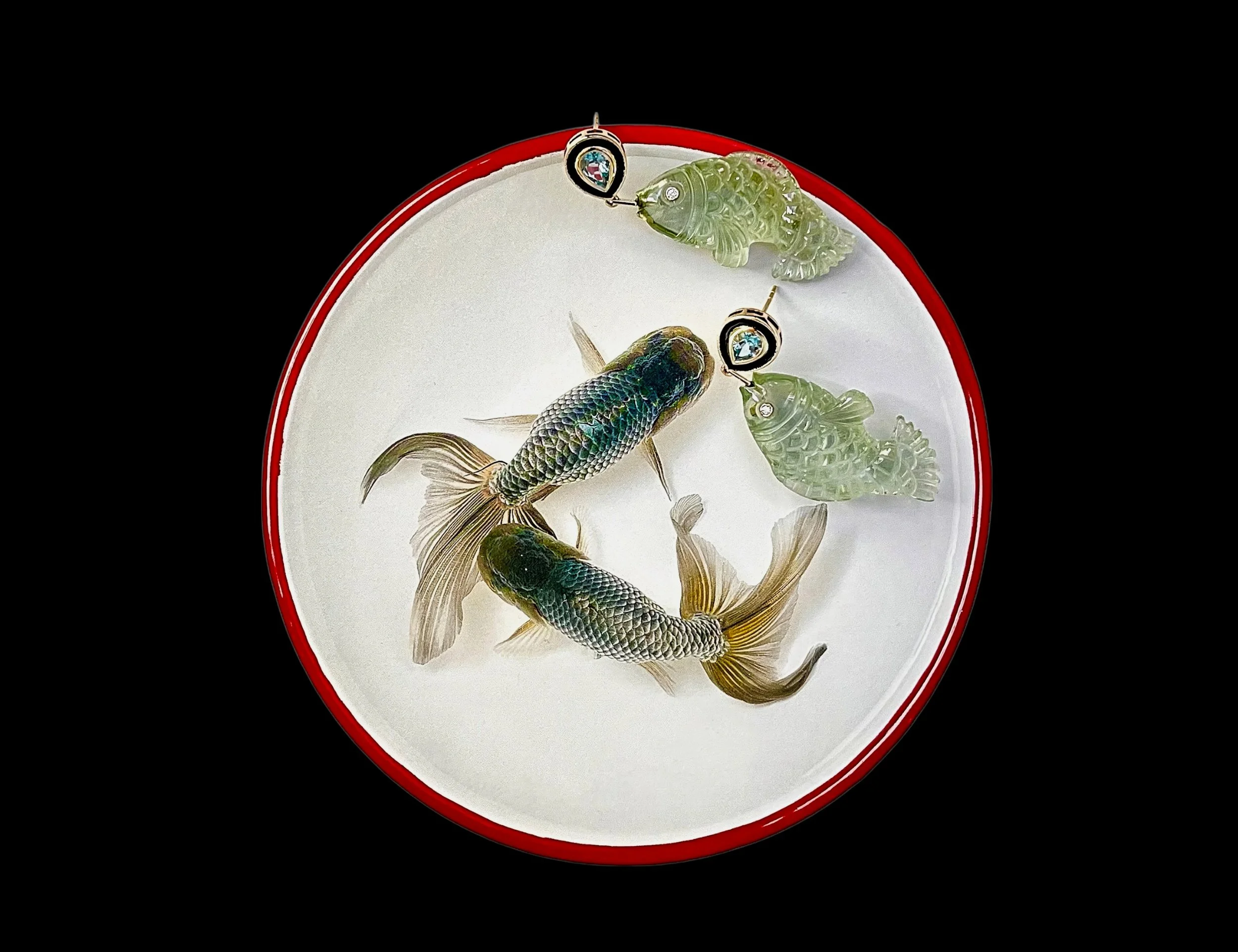 Close-up of a white dish with a red rim, containing several small fish and jadeite carvings, with a black background.