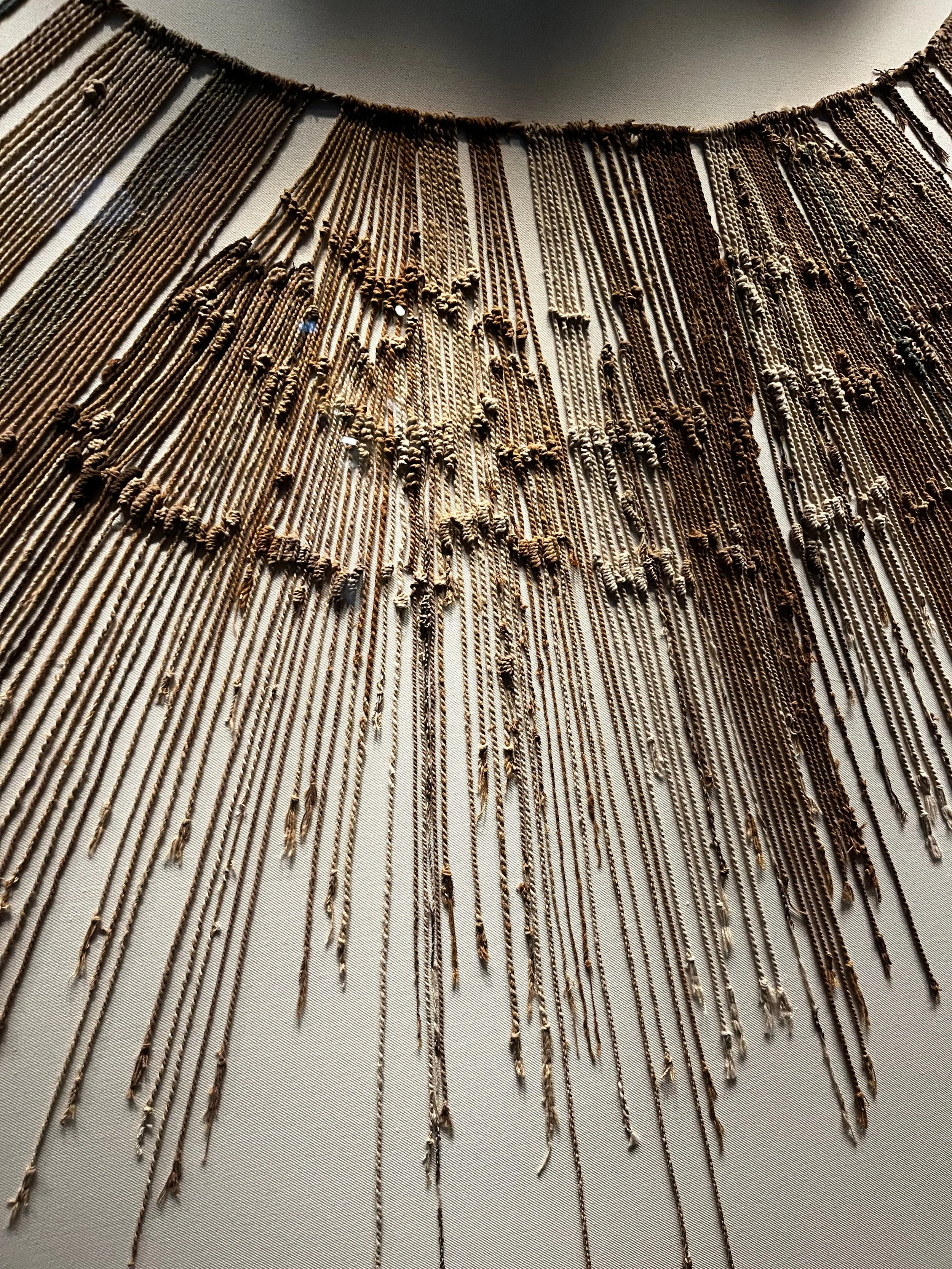 An intricate necklace made of multiple strands of brown and brass-colored beads.