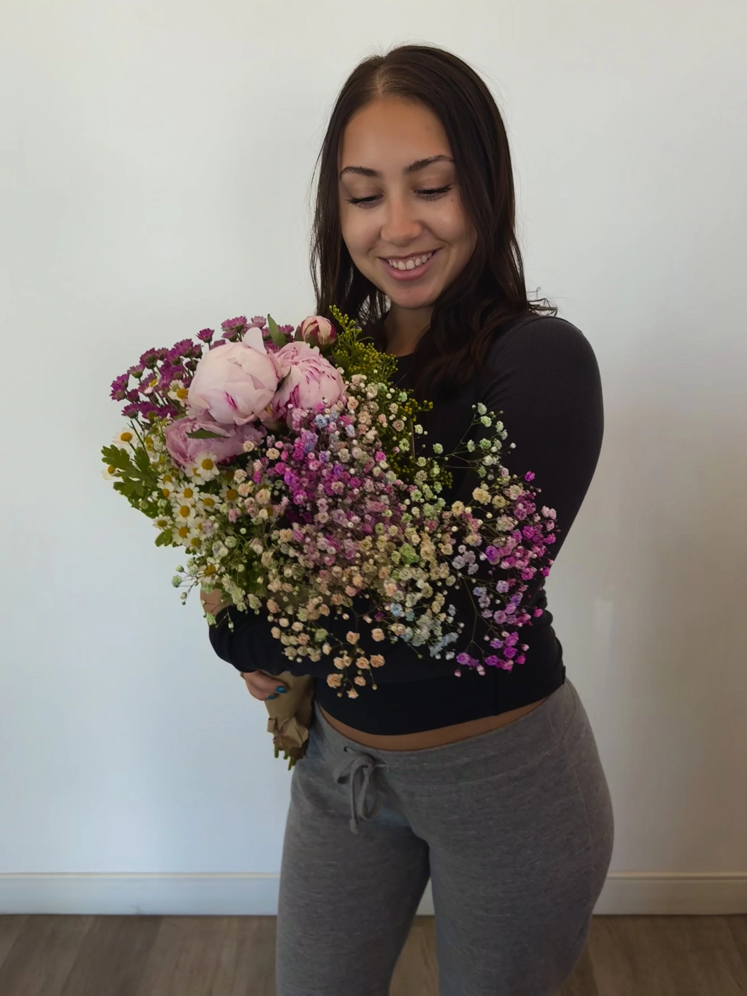 Portrait of Lexy, professional Esthetician and owner of Fable and Flora Esthetics in Sacramento, holding flowers.
