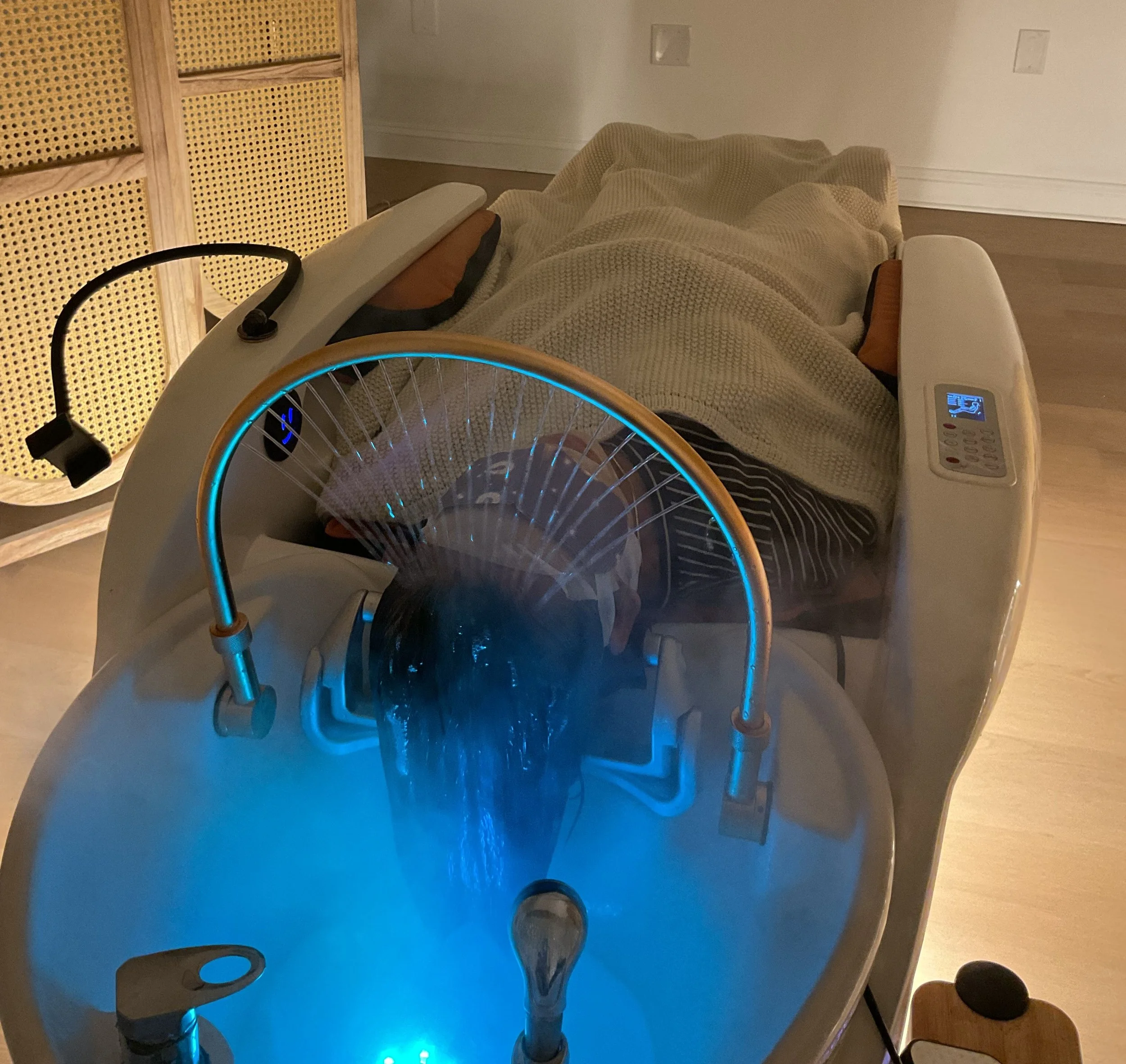 A person lying on a full body massage bed, while getting halo therapy and steam therapy.