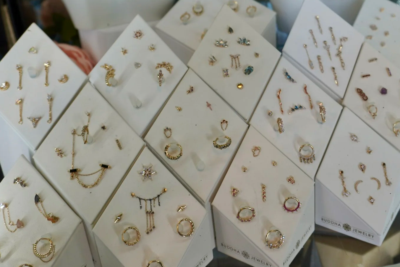Display of multiple jewelry earrings on white cards at a store or market.