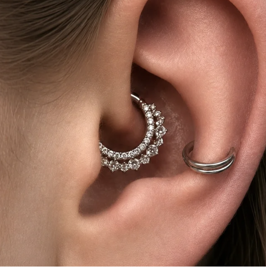 Close-up of a person's ear with a hoop earring decorated with rhinestones and a simple silver ring earring.