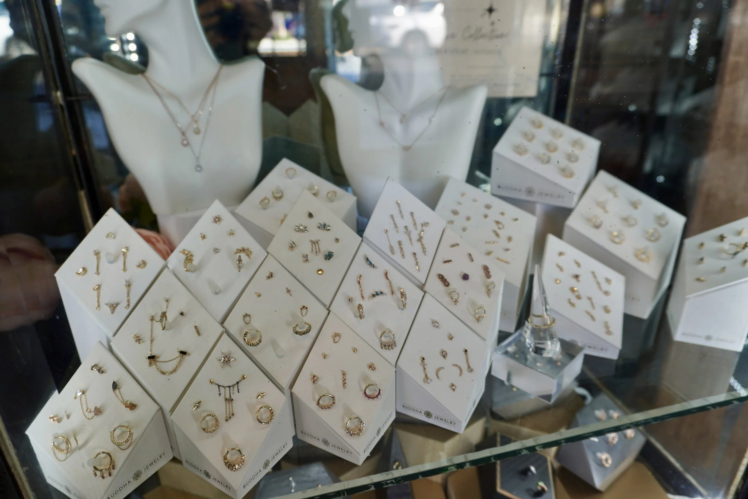 Display of various jewelry pieces, including rings, necklaces, and earrings, in a glass case at a jewelry store.
