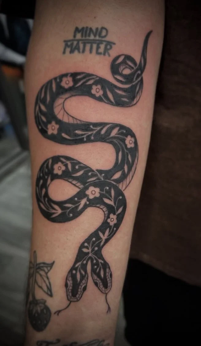 Tattoo of a snake with floral patterns, and the words "MIND" and "MATTER" above it.