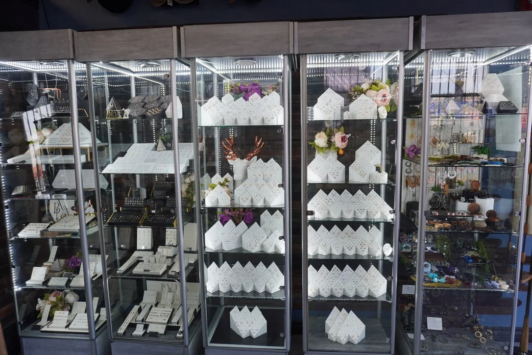 Display case with jewelry, decorative boxes, and flowers in a store.