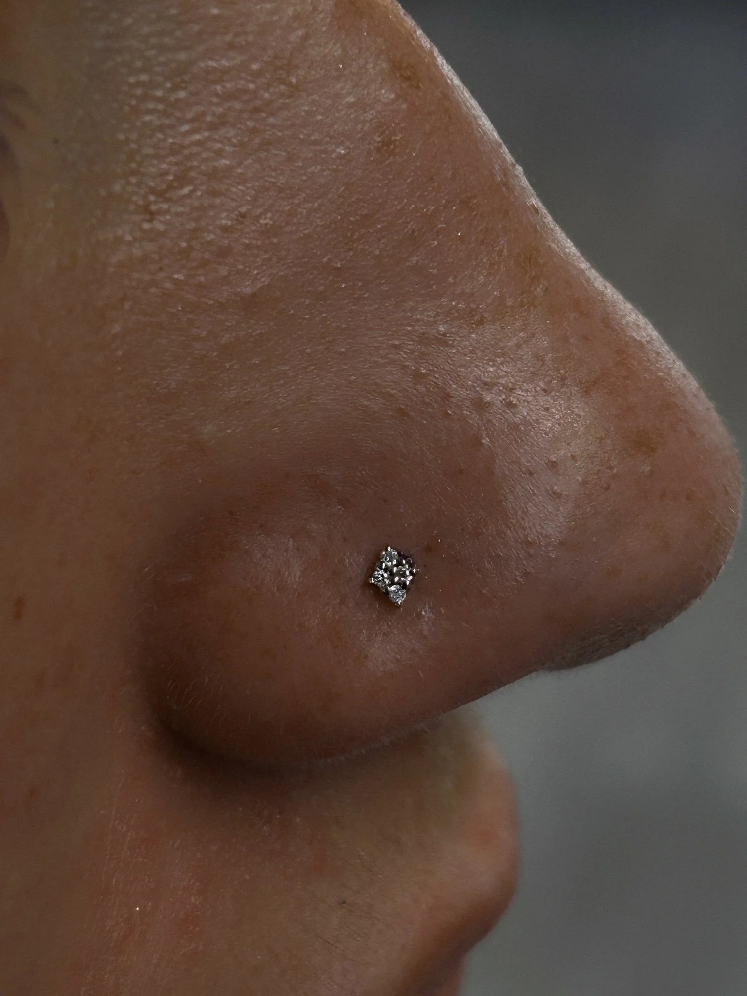 Close-up of a person's nose with a small diamond nose piercing.