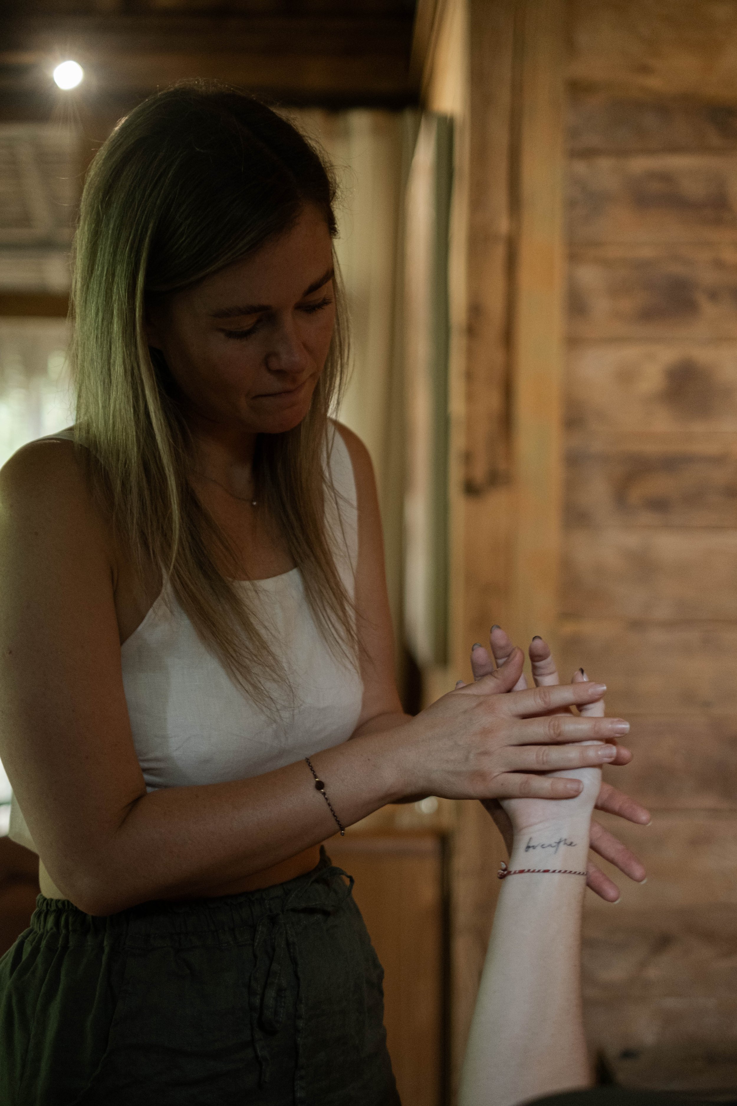 Alex facilitating a facilitated breath repatterining breathwork session, holding a client's hand during hands-on breathwork support.
