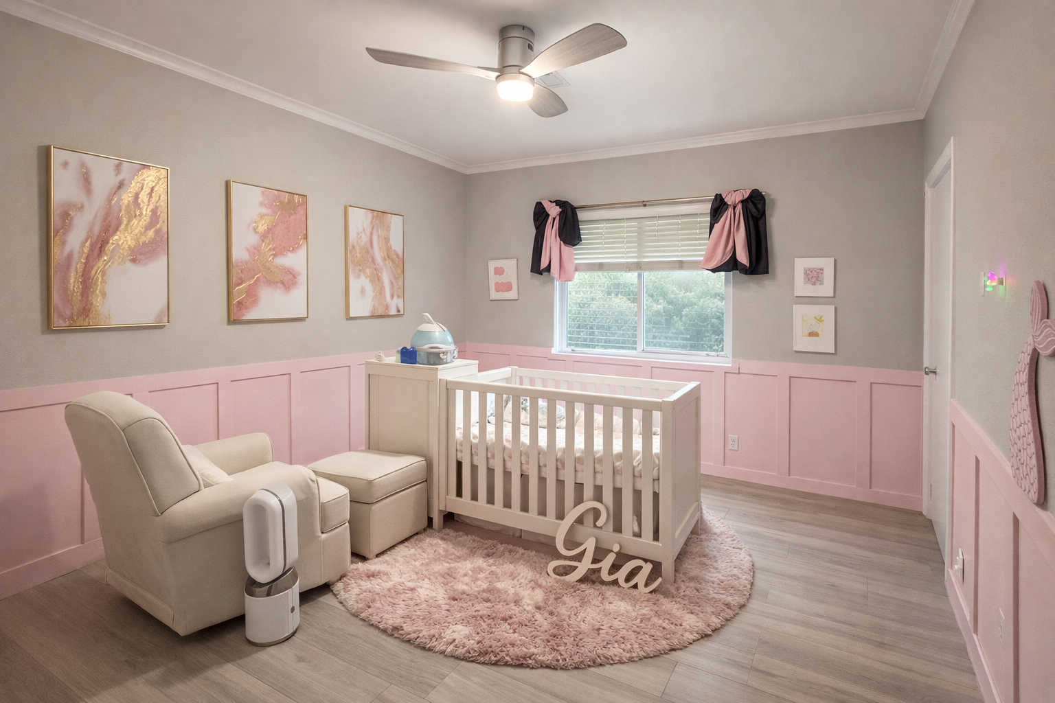 Nursery room with pink wainscoting, a white crib, a beige armchair with matching ottoman, pink fuzzy rug, wall art, a window with pink and black curtains, and a ceiling fan.
