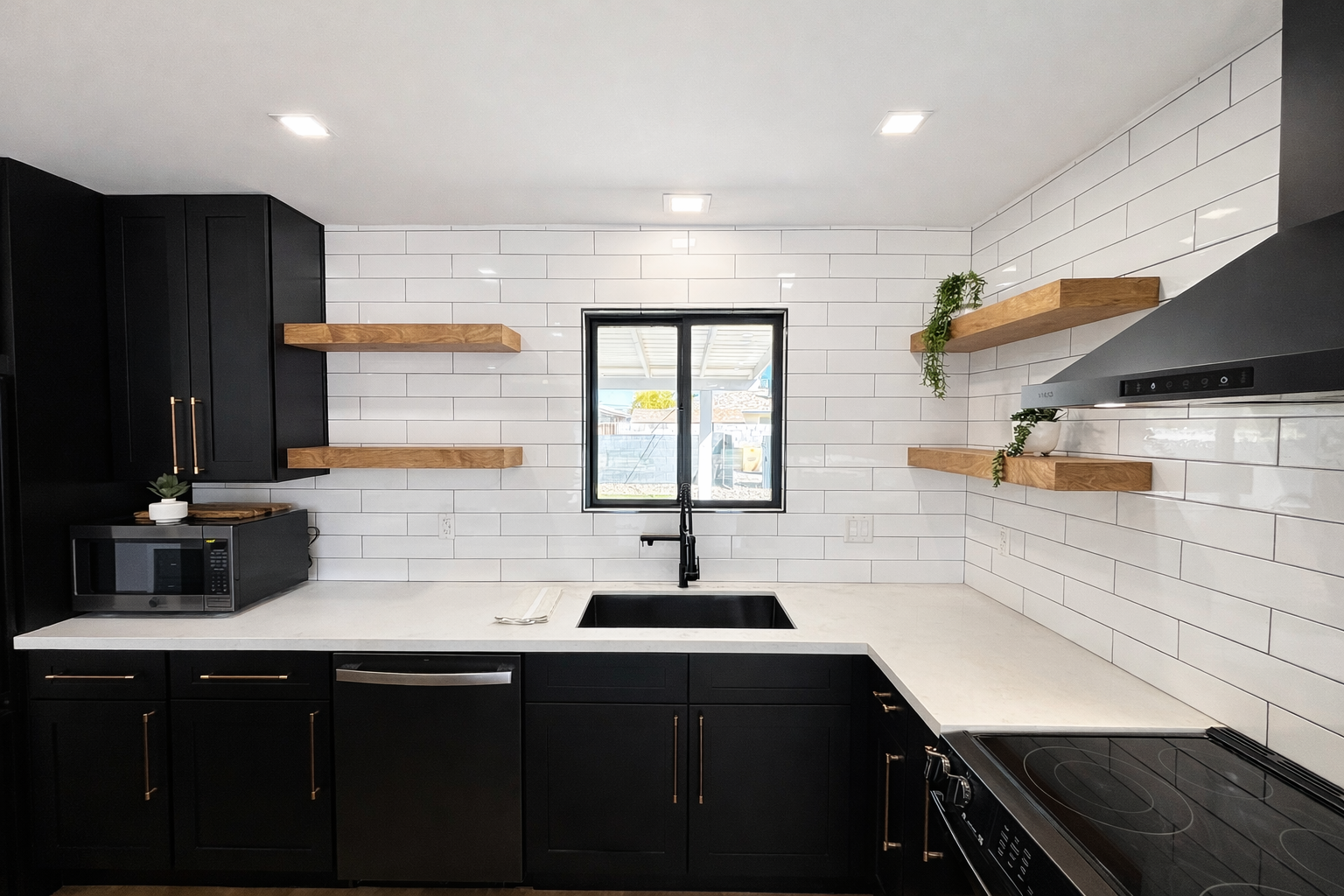 Modern kitchen with black cabinets, white subway tile backsplash, wooden open shelves, a black sink, a stove, and a small window above the sink.