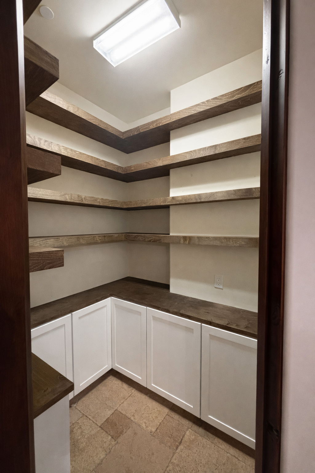 Empty walk-in pantry with wooden open shelves and white cabinets at the bottom.