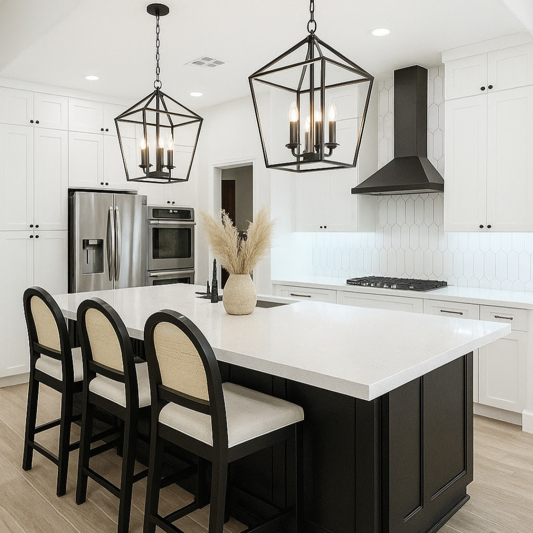 Modern kitchen with white cabinets, black island, pendant lights, stainless steel refrigerator, built-in oven, black vent hood, white backsplash, beige floor, and a vase with pampas grass.