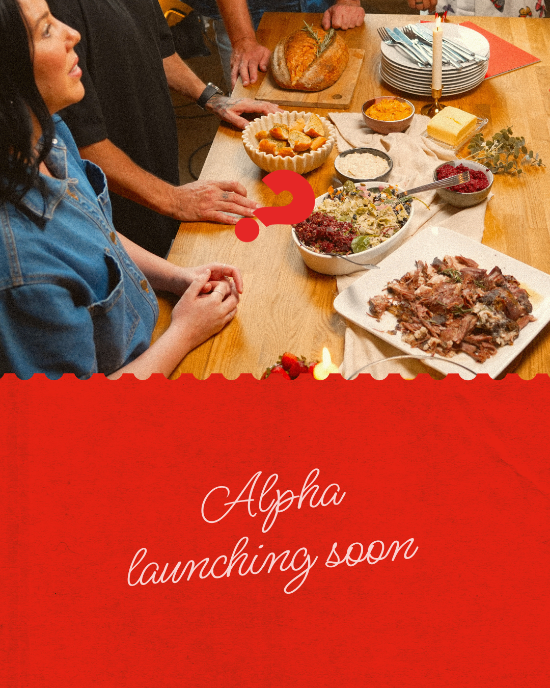 A table set with various dishes including bread, salad, carved meat, and dessert. People are gathered around, with one woman in a blue denim shirt and others preparing for a meal. The foreground has a red overlay with the text 'Alpha launching soon'.