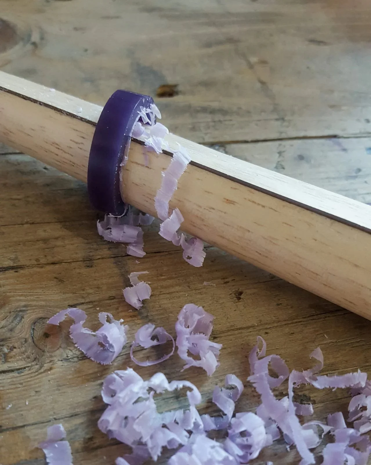Ein Bohrer, der in ein Holzstück eingedrungen ist, mit Holzspänen, die um den Bohrer herum liegen.