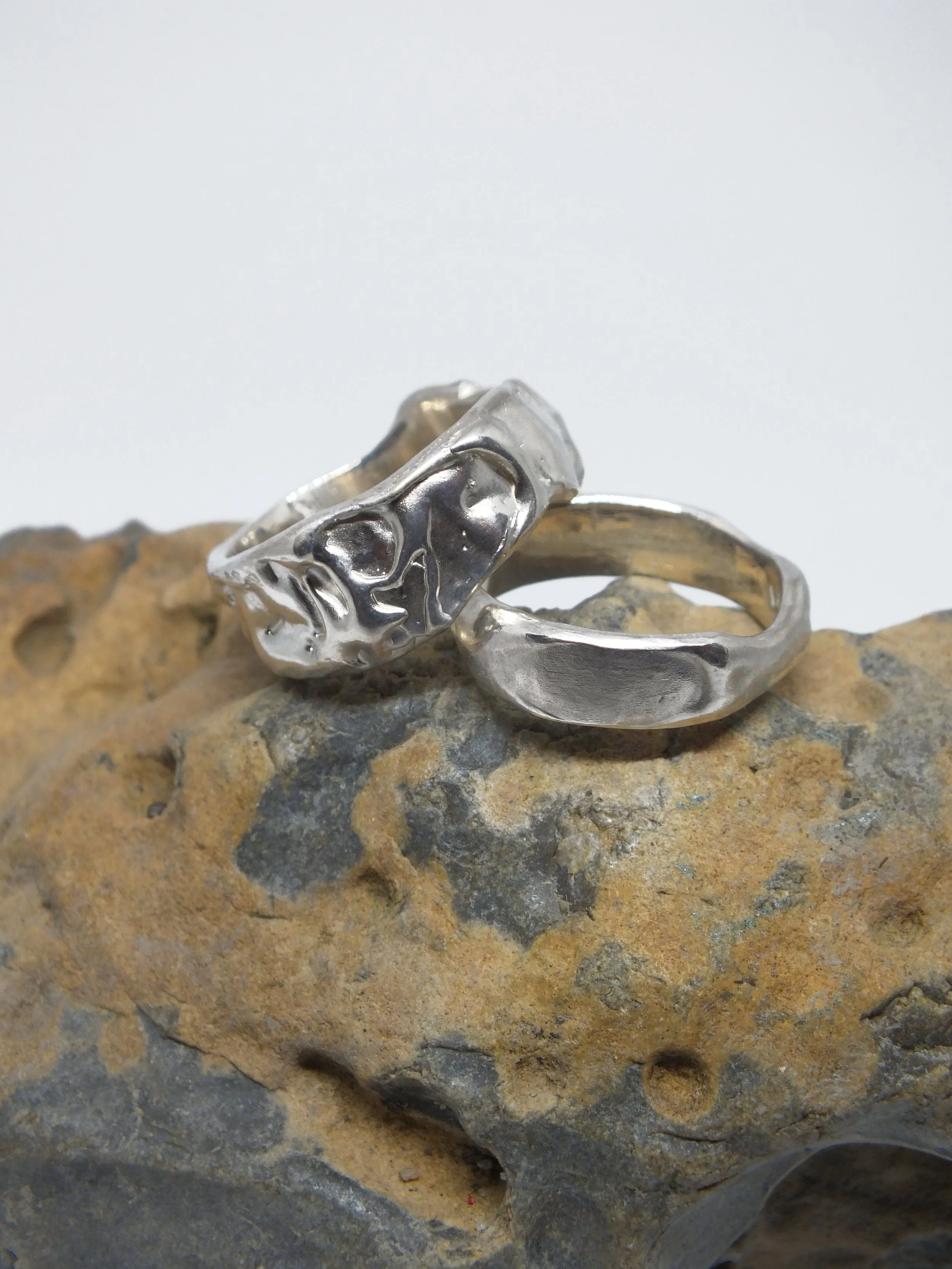 Silberne Ringe mit einer angeschmolzenen Struktur auf einem Felsen