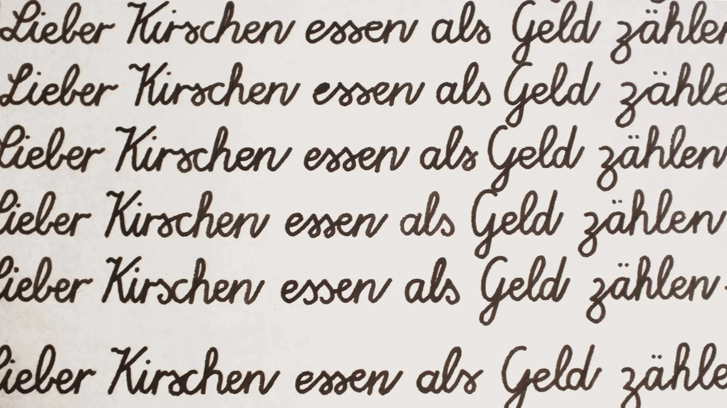 Handgeschriebener Text in deutscher Sprache, der mehrfach wiederholt wird: 'Lieber Kirschen essen als Geld zählen'.