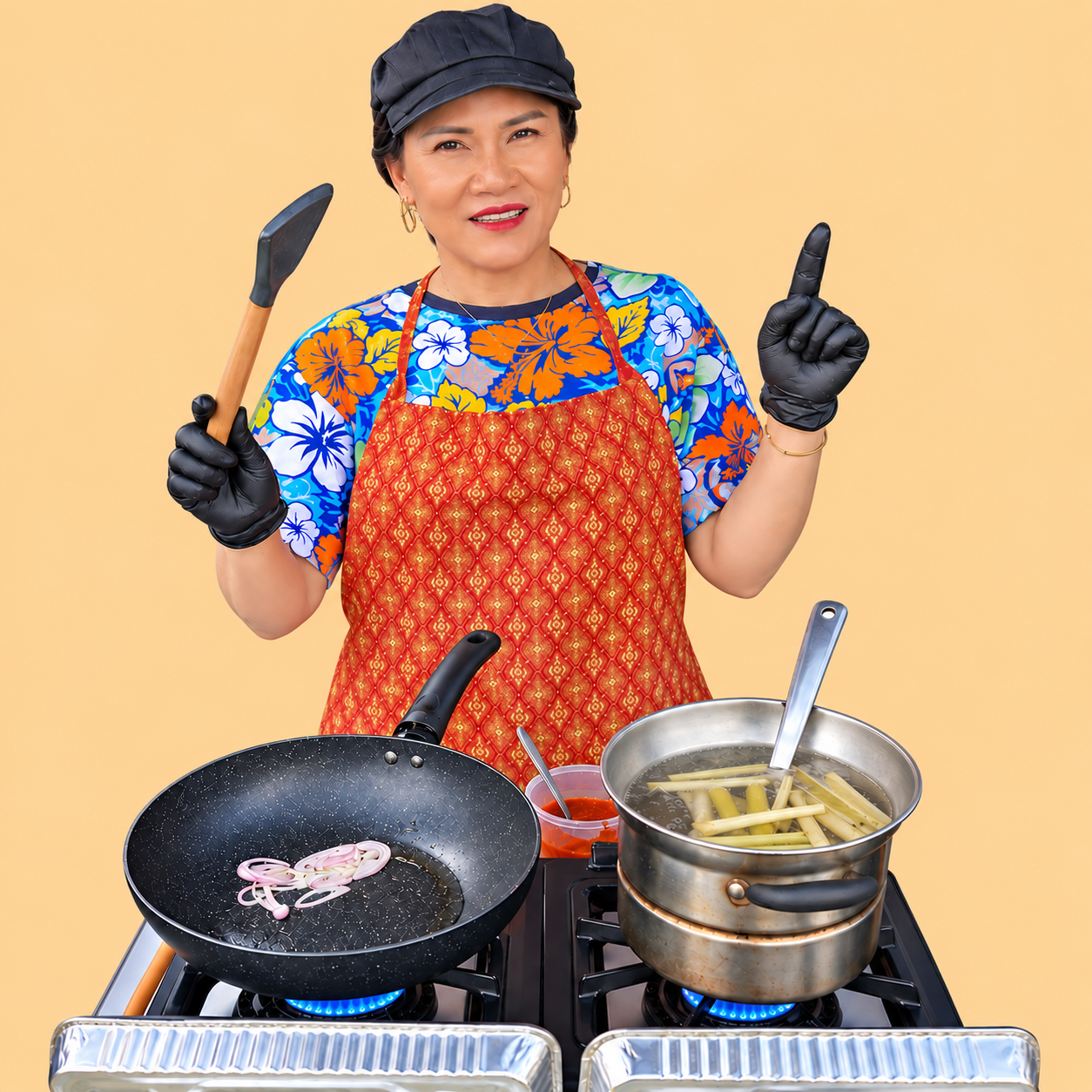 A woman in a colorful floral shirt and red apron, wearing a black cap and gloves, standing by a stove with two pots of boiling water, one containing bamboo shoots and the other with penne pasta, holding a spatula and pointing with her finger.