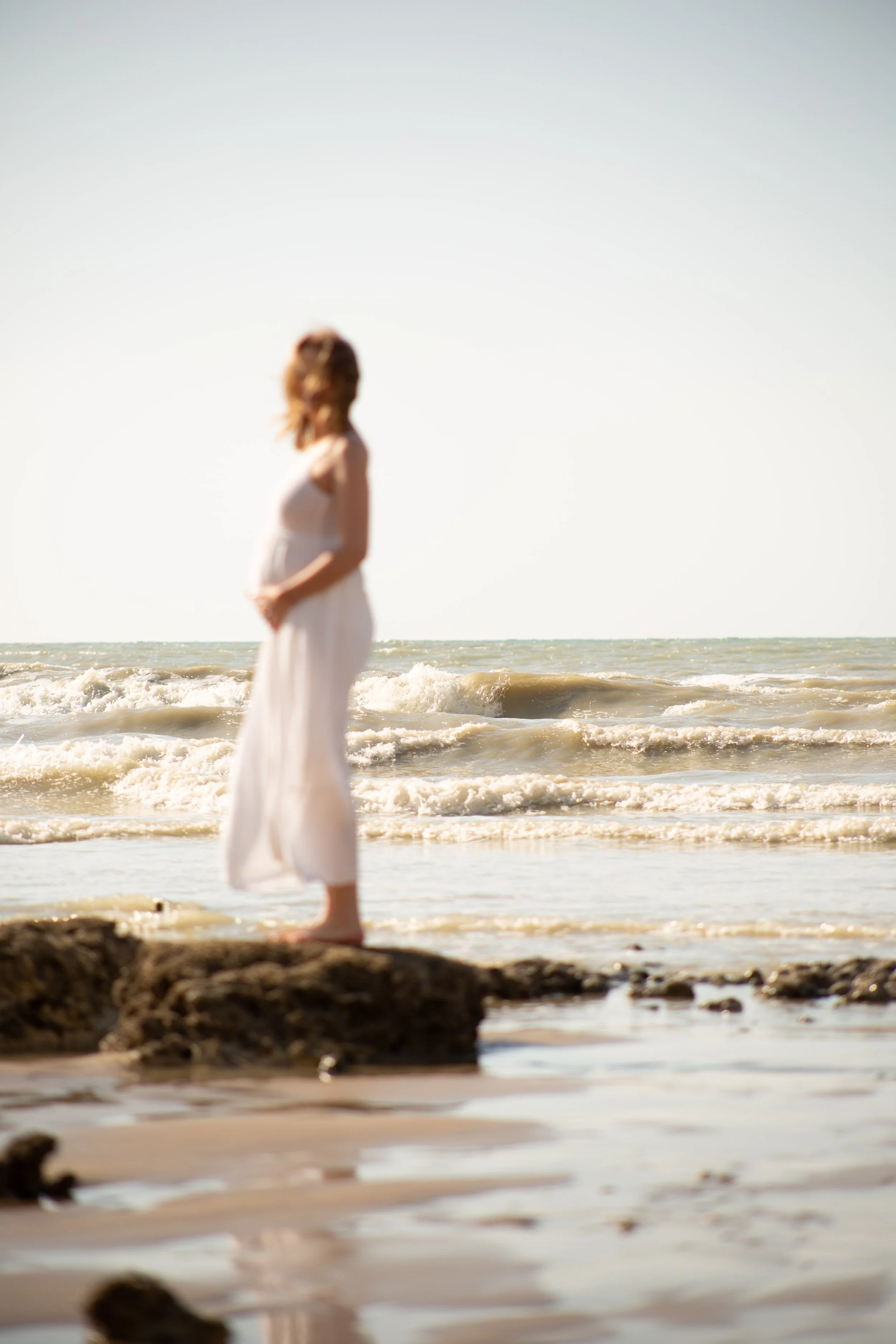 Silhouette de la future mère en robe blanche face à la mer — studio nepita