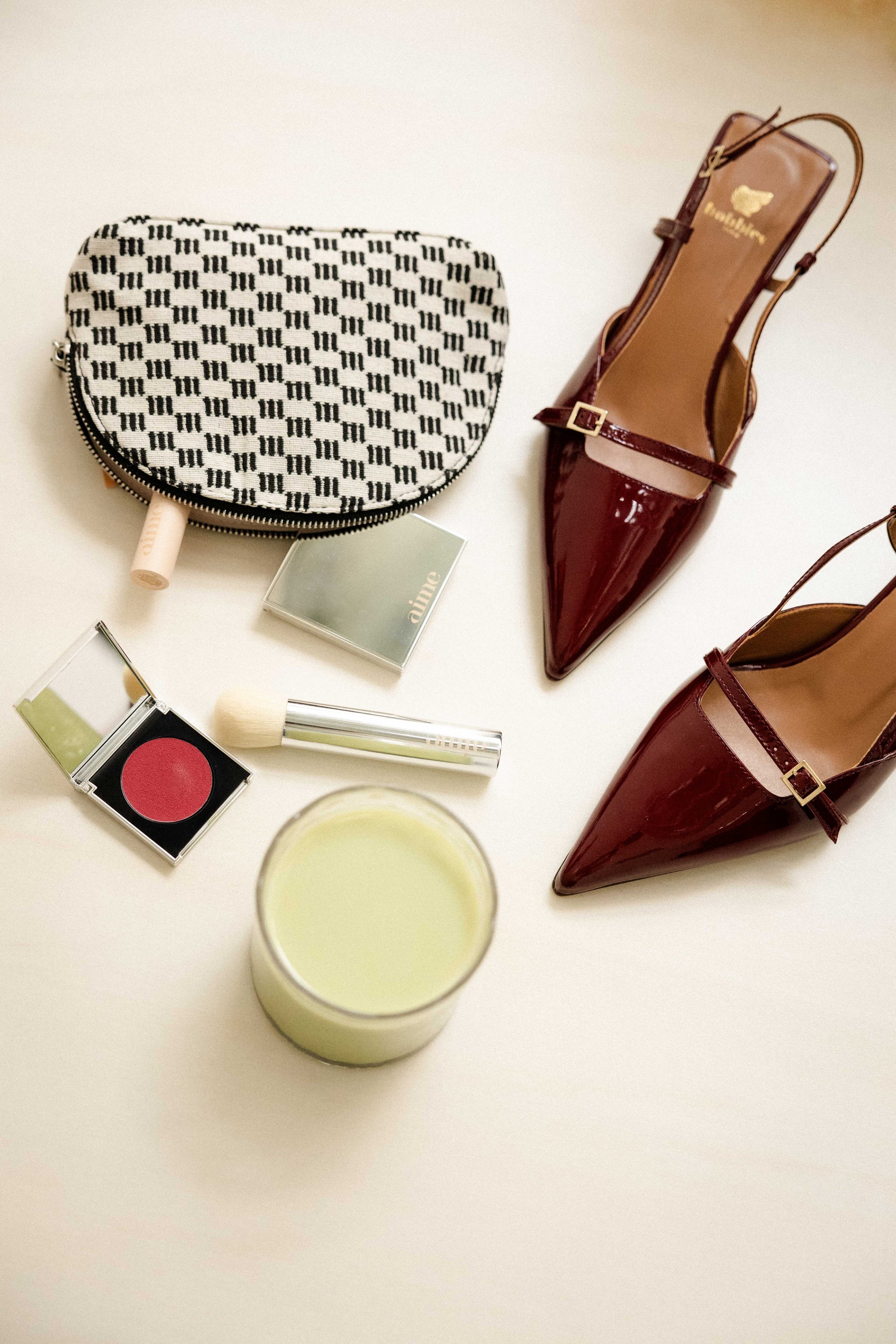Flatlay associant maquillage Aime, trousse graphique et escarpins vernis — studio nepita