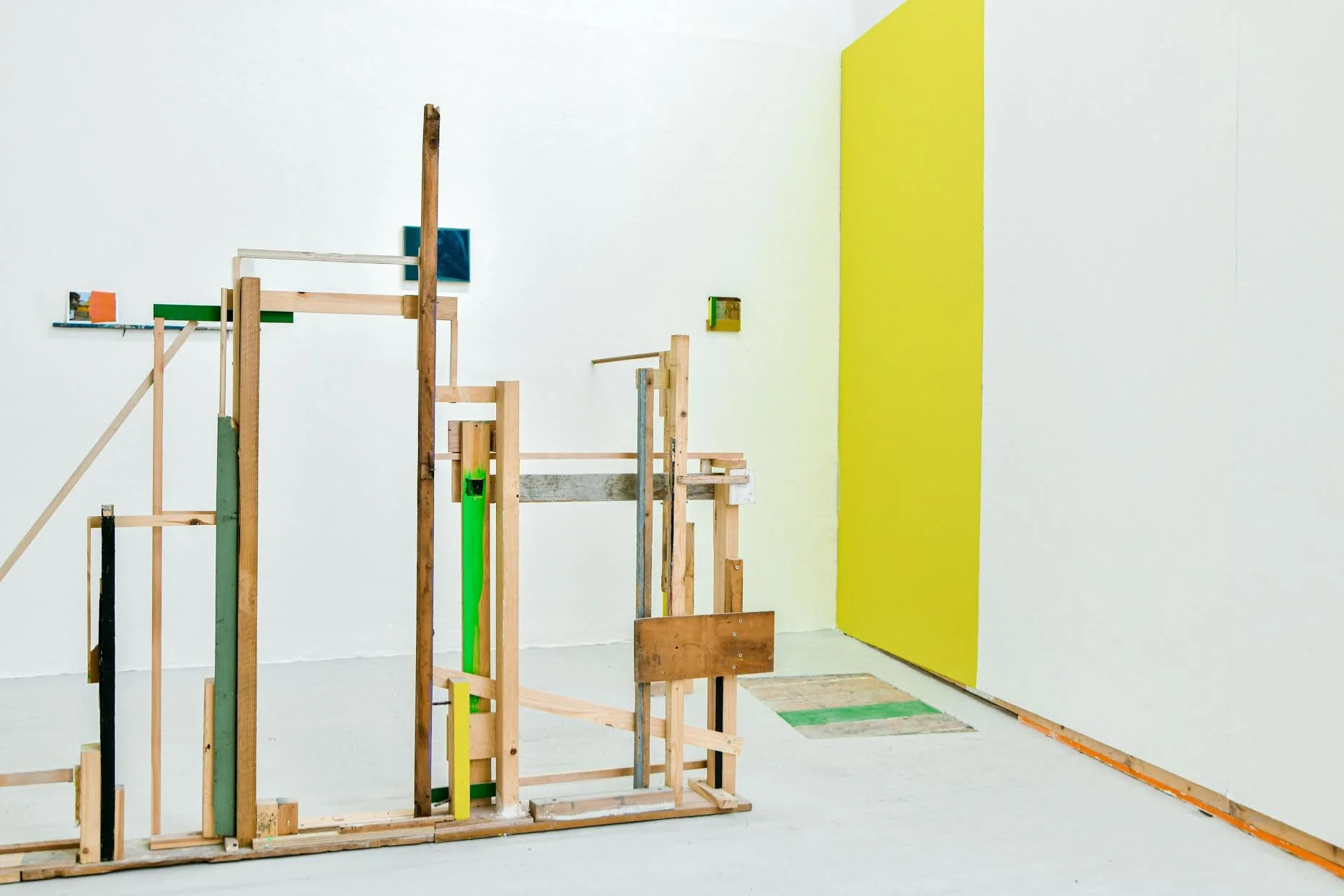 Art installation with wooden structures and colorful painted surfaces in a gallery.