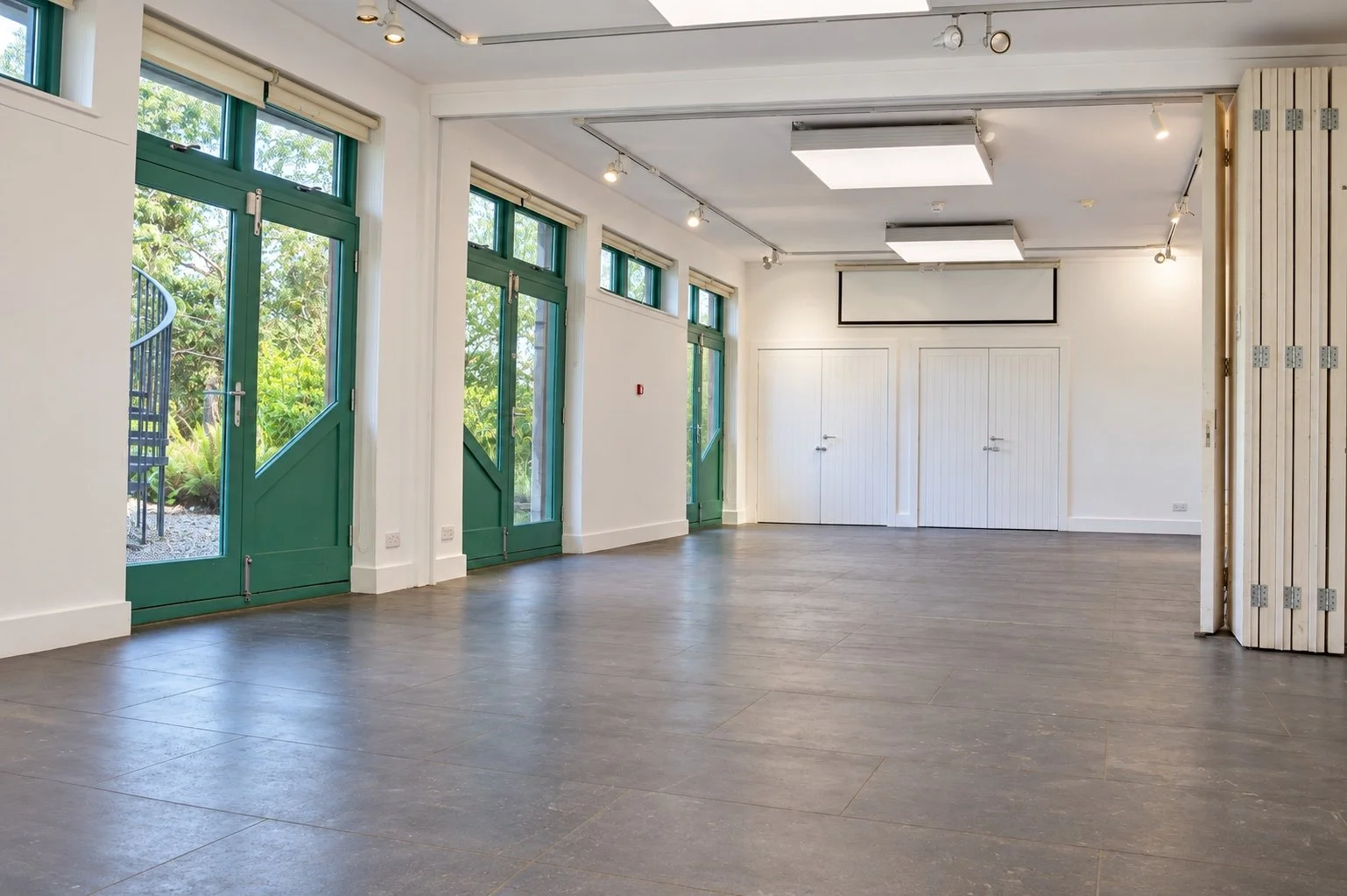 Spacious connected classrooms with green garden doors and flexible open floor.