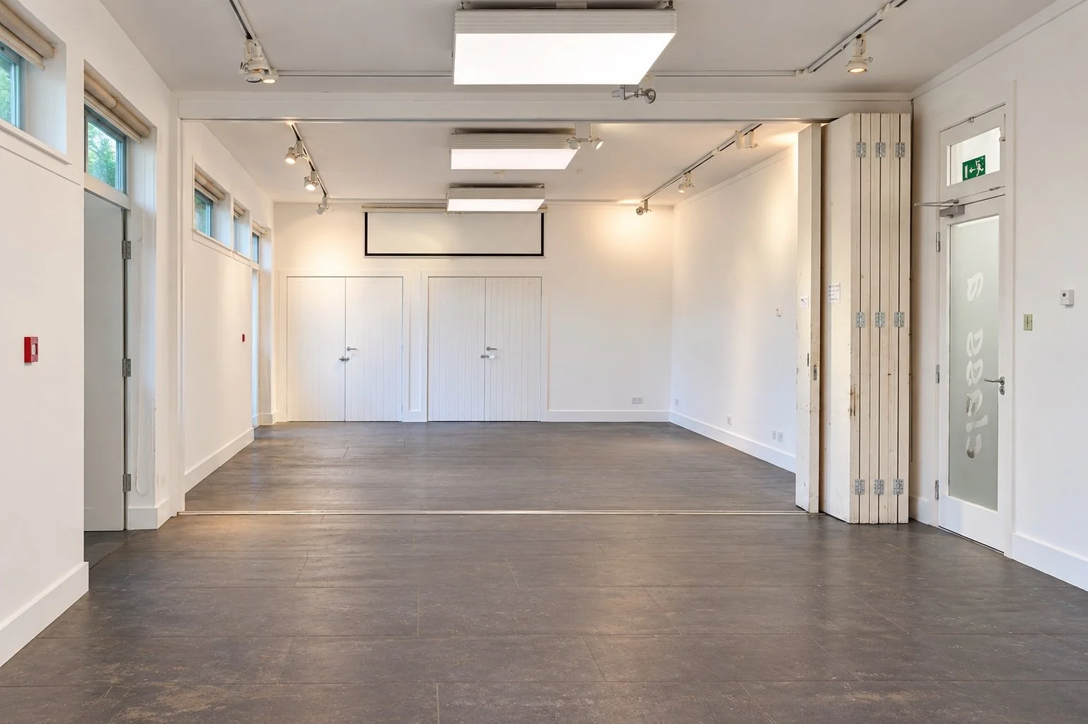 Bright connected classrooms with folding partition and projector screen.