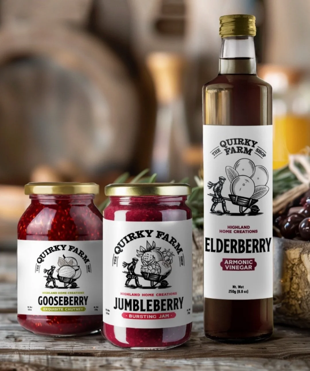 Two jars and one bottle of homemade Quirky Farm Shop products, including Gooseberry chutney, Jumbleberry jam, and Elderberry vinegar displayed on a wooden surface with a rustic background.