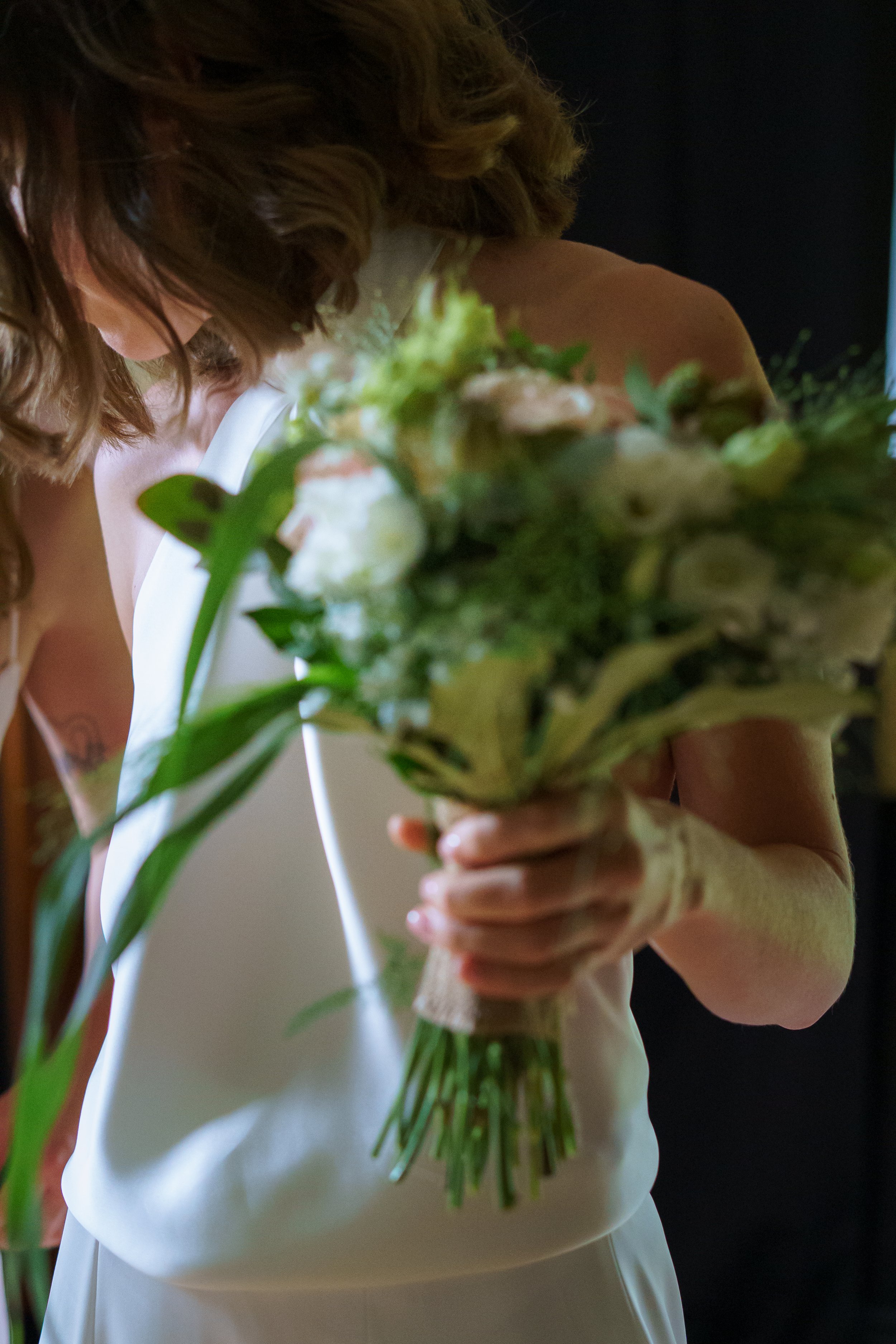 Une personne portant une robe blanche tient un bouquet de fleurs dans ses mains.