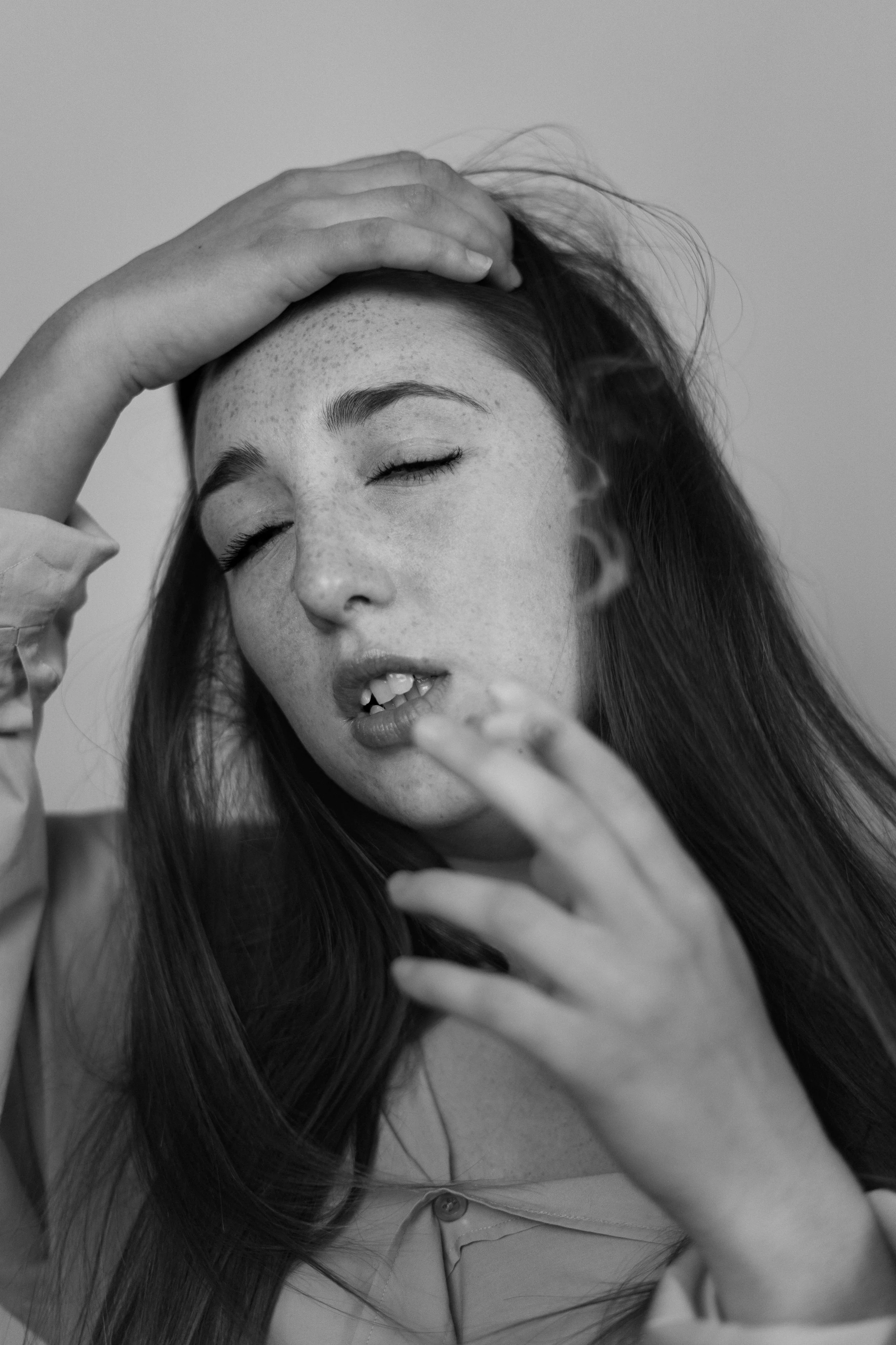 Jeune femme avec les yeux fermés, les cheveux longs, main sur la tête, expression de contemplation ou d’émotion.