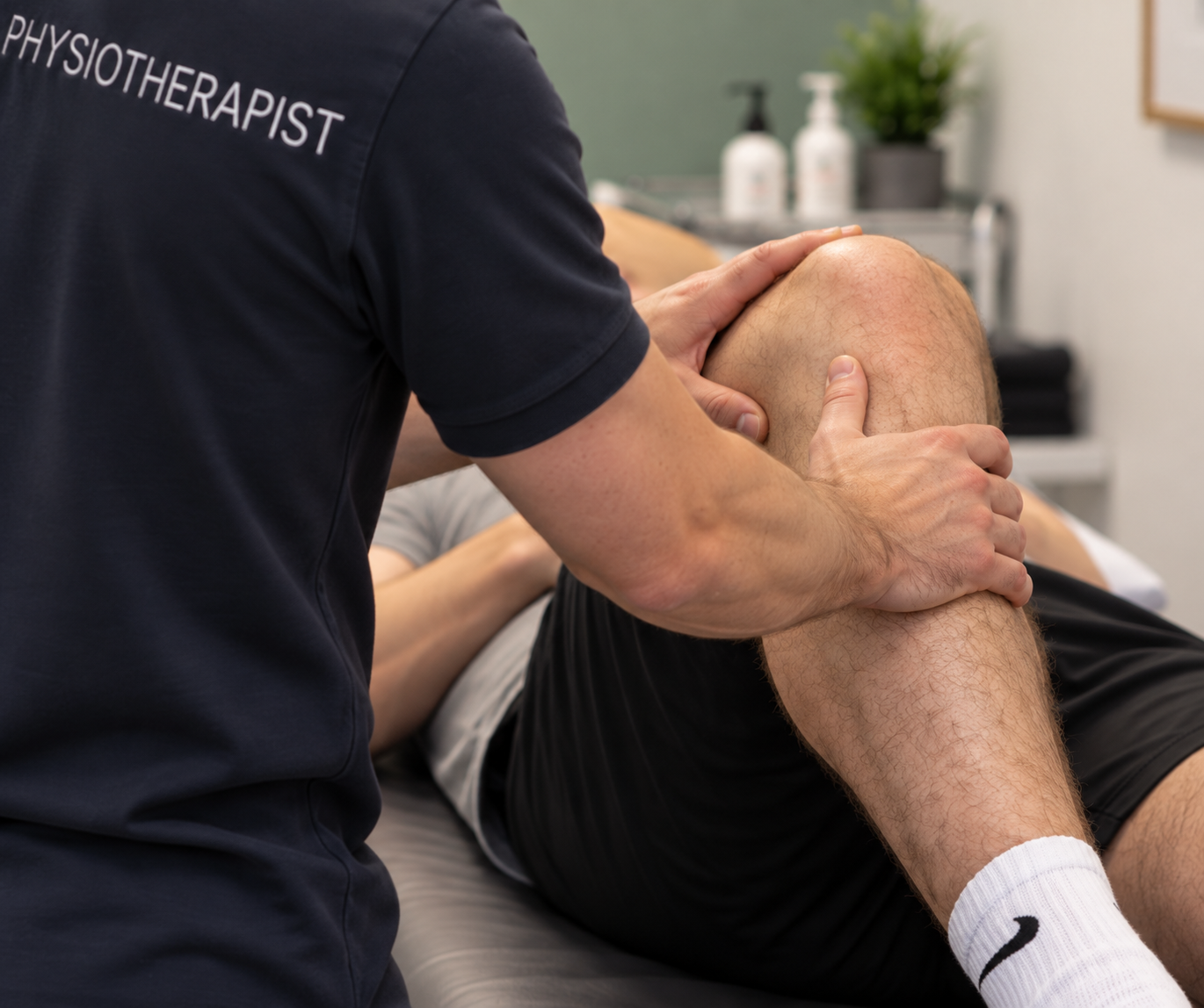 A physiotherapist providing knee therapy to a patient lying on a treatment table.