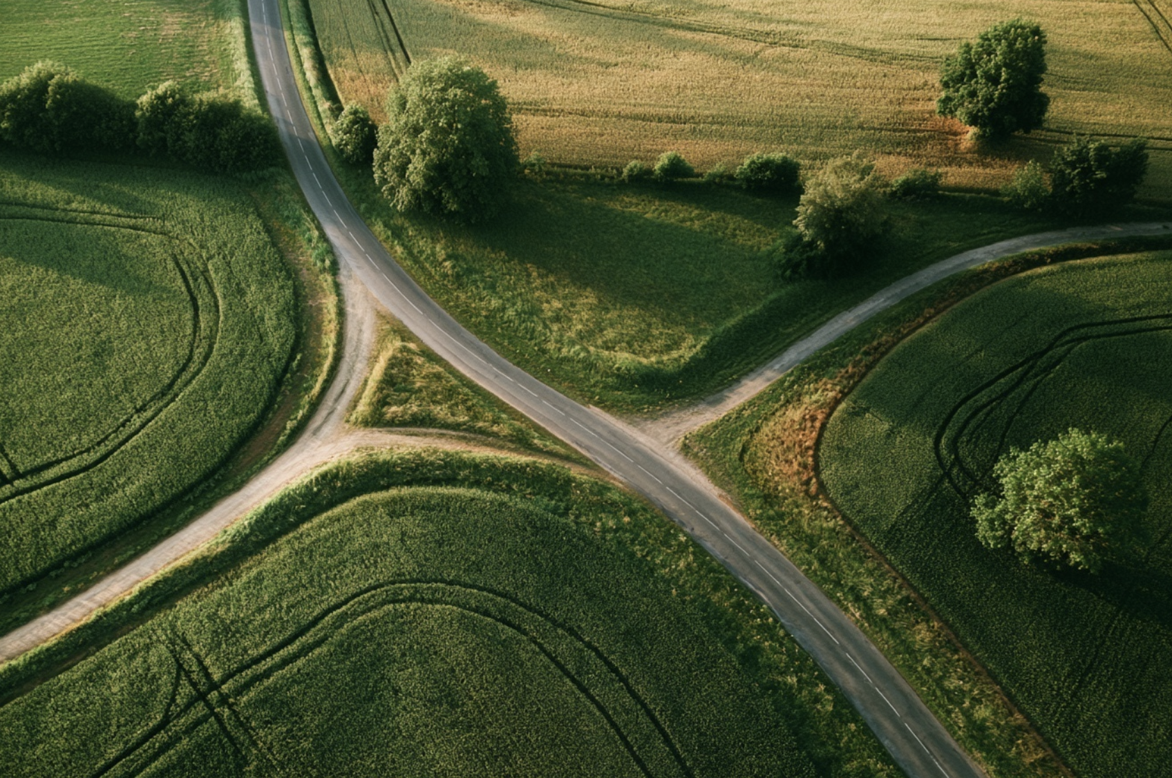 An aerial view of a rural landscape with roads, green farmland, and trees.