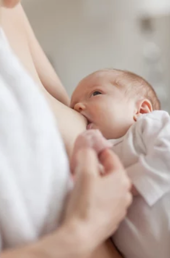 A baby breastfeeding from a woman's breast.