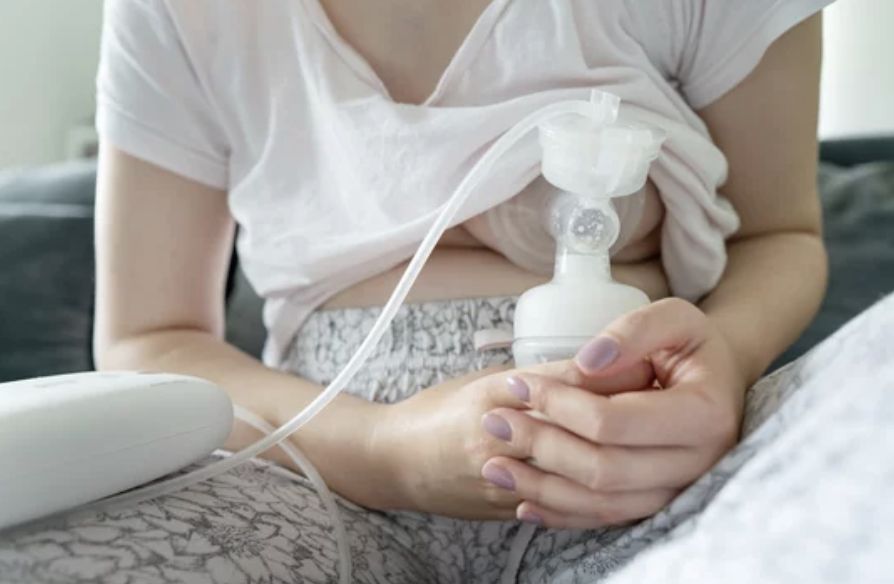 Person in hospital bed using a breast pump to express milk