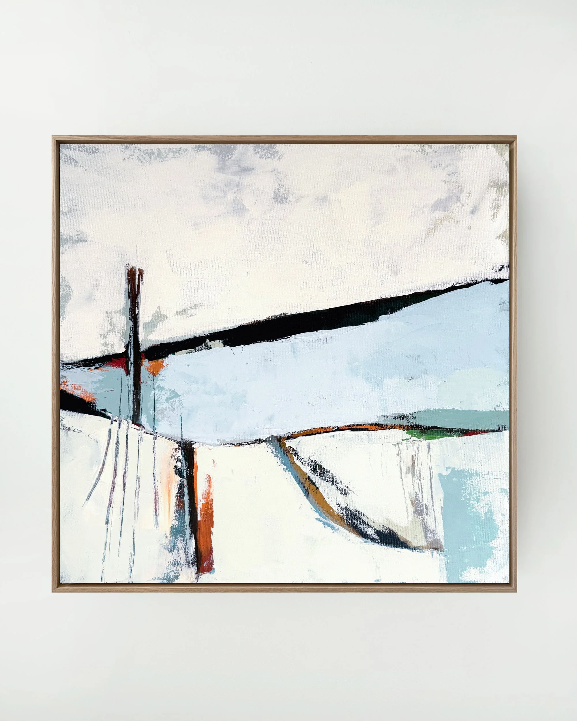 Close-up of an abstract painting with black, brown, orange, and blue brushstrokes on a white background, framed in light wood.