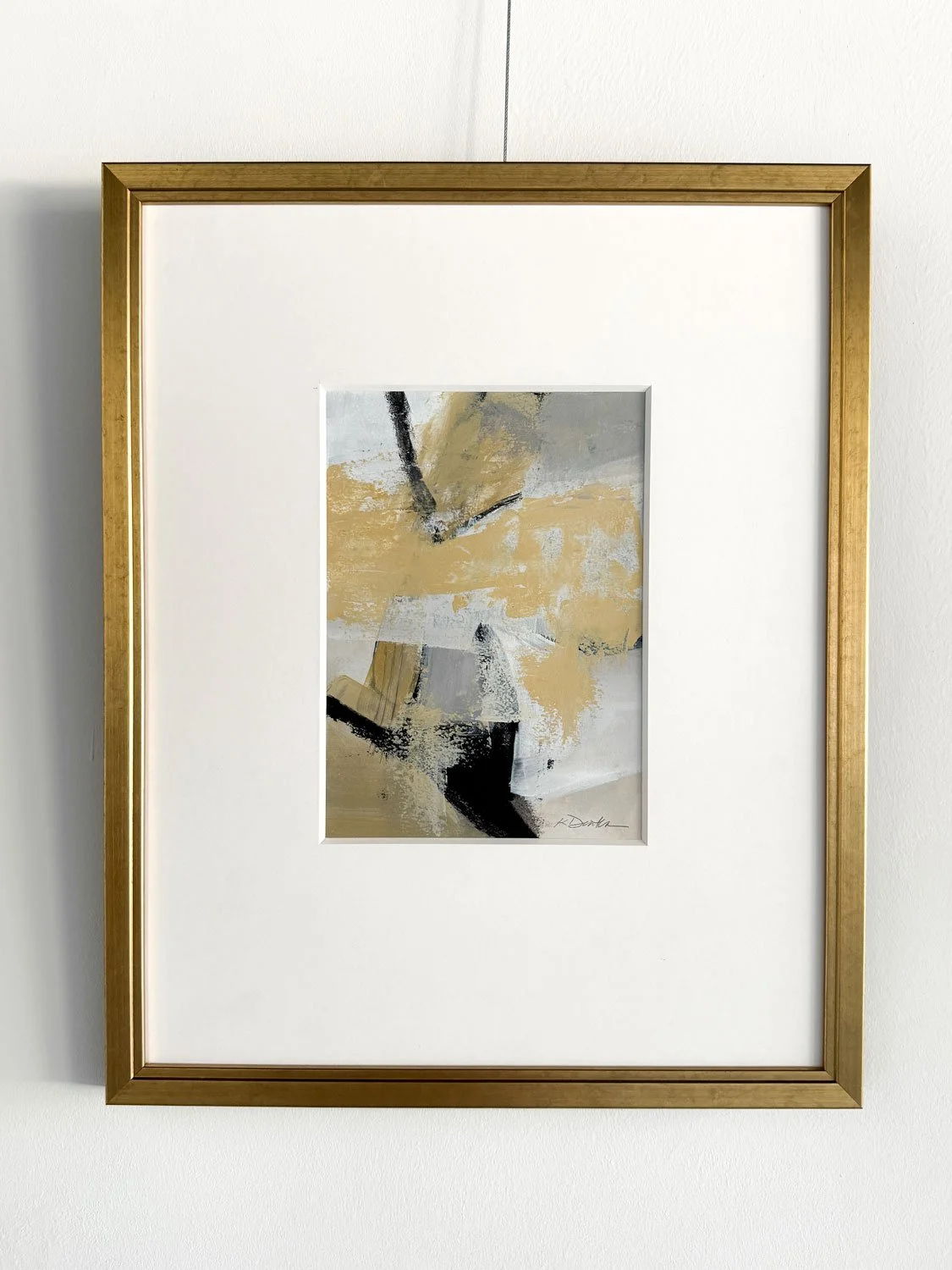 Black & Gold 1, abstract work on paper by Karyn Denten with layered gold, gray, neutral tones, and bold black marks, framed in gold.