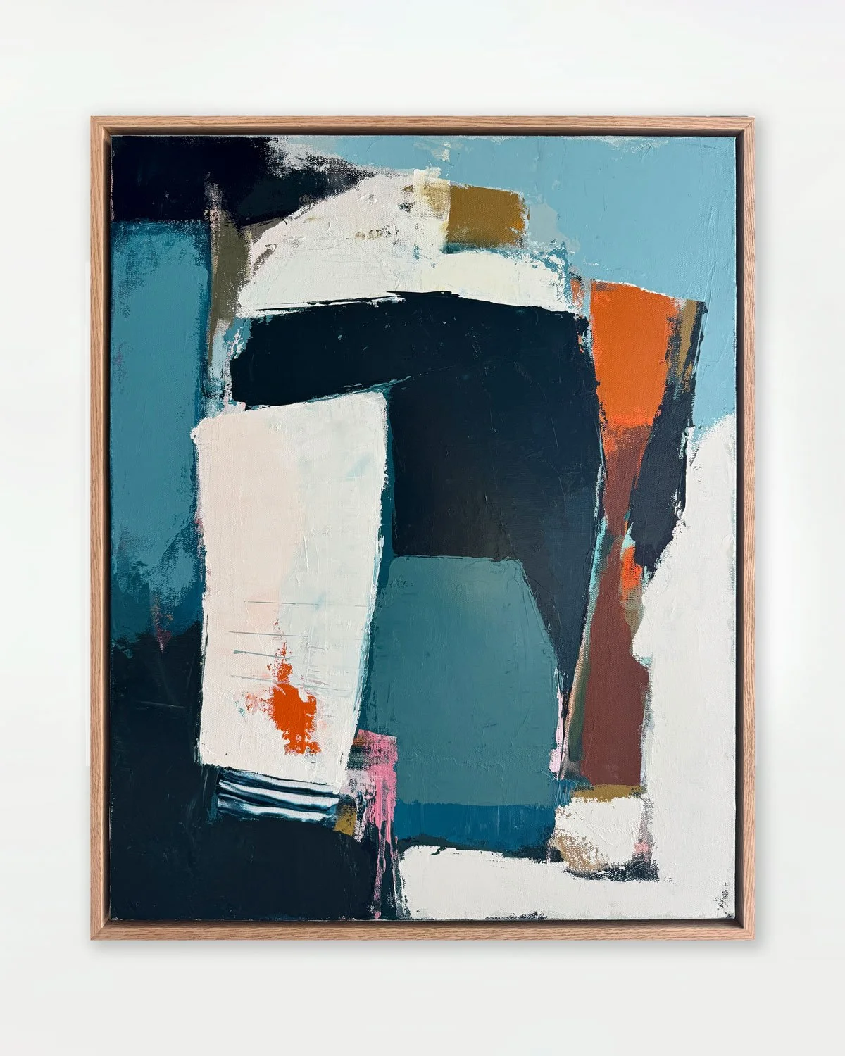 Abstract painting with bold shapes and colors, framed in wood, hanging on a white wall.