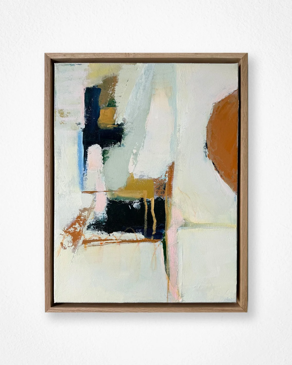 Abstract painting with various colors including black, white, yellow, green, blue, and brown, framed with a wooden border, hanging on a white wall.