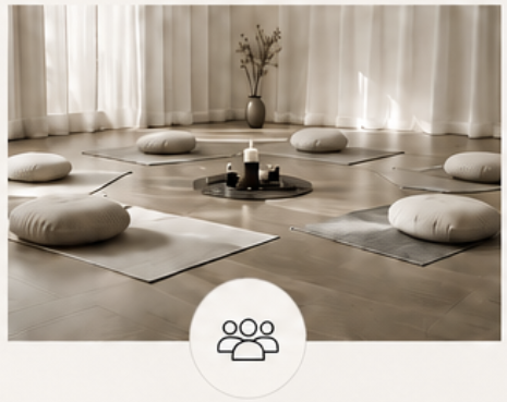 Ein meditativer Raum mit acht Yogamatten, Sitzkissen, einer Vase mit Zweigen und Kerzen in der Mitte.