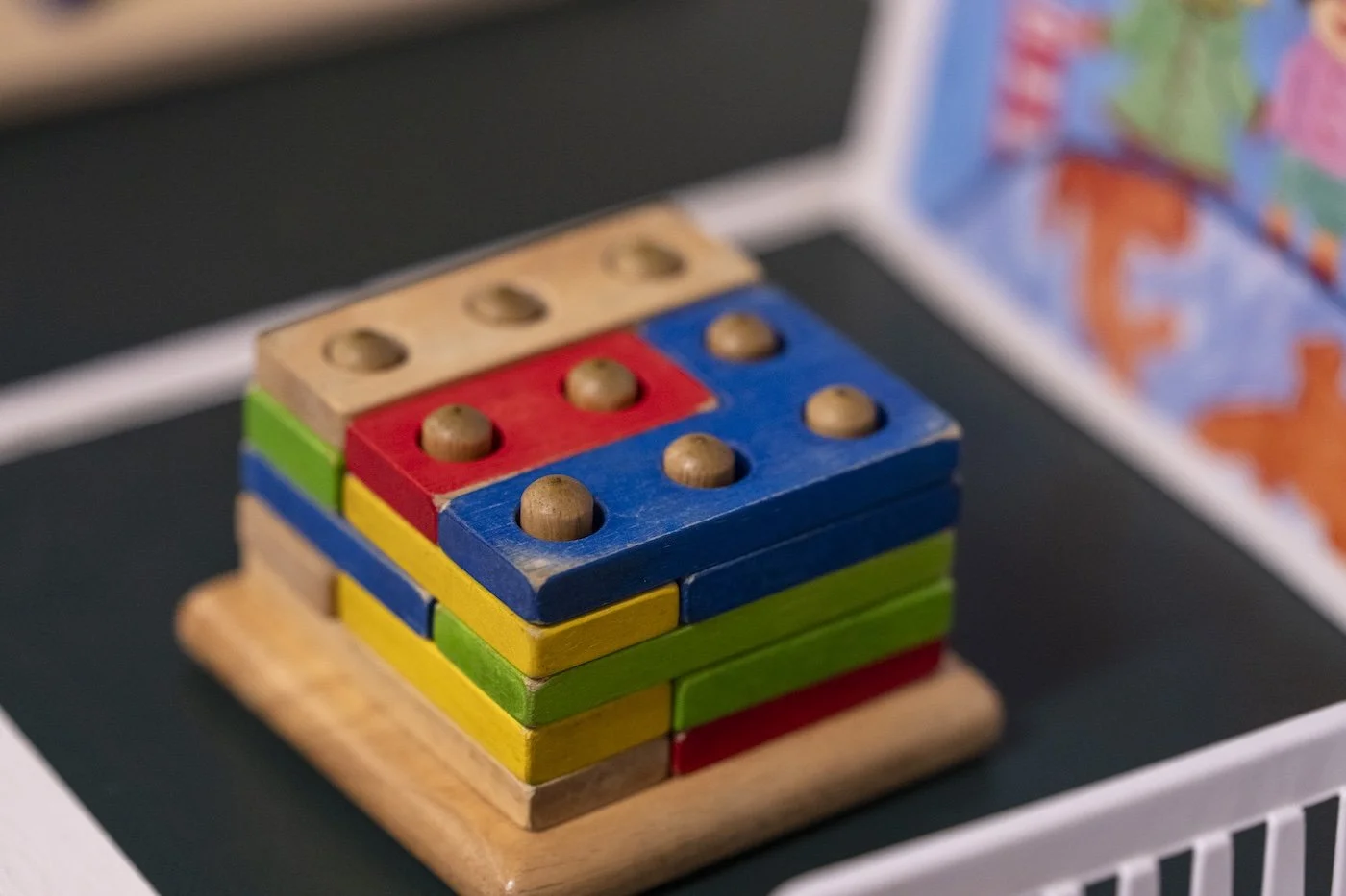 Colorful wooden stacking toy with numbered pieces and rounded wooden pegs.