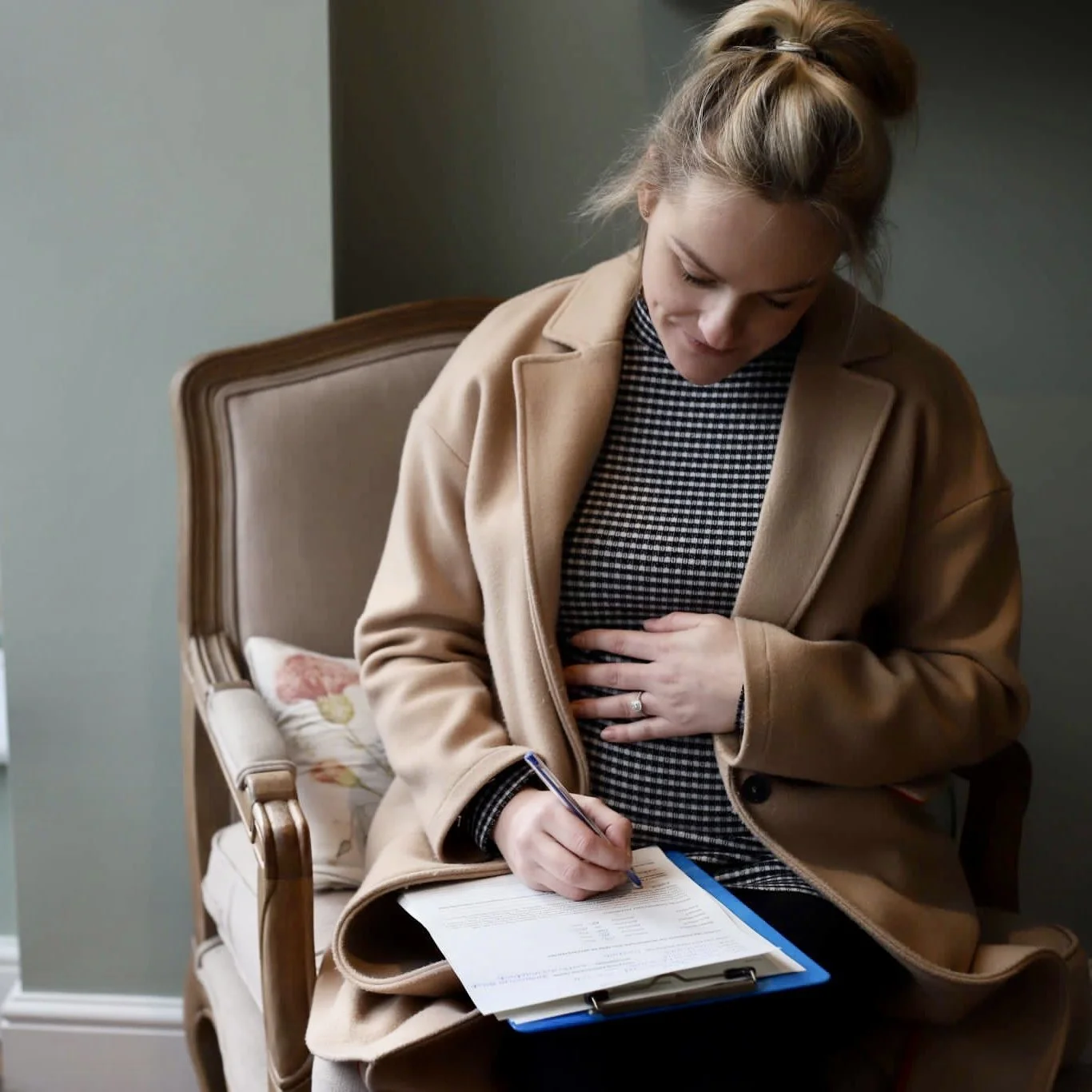 A pregnant lady filling out a consultation form before her Pregnancy or Post natal massage.