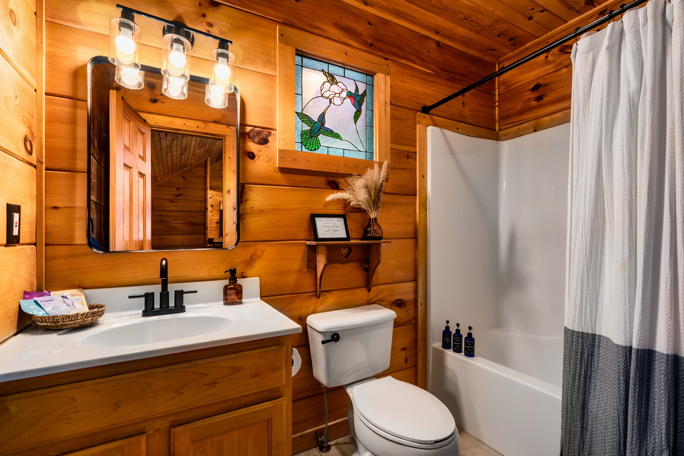 Blue Sage Hideaway Upper level bathroom vanity with tub and stained glass hummingbird window