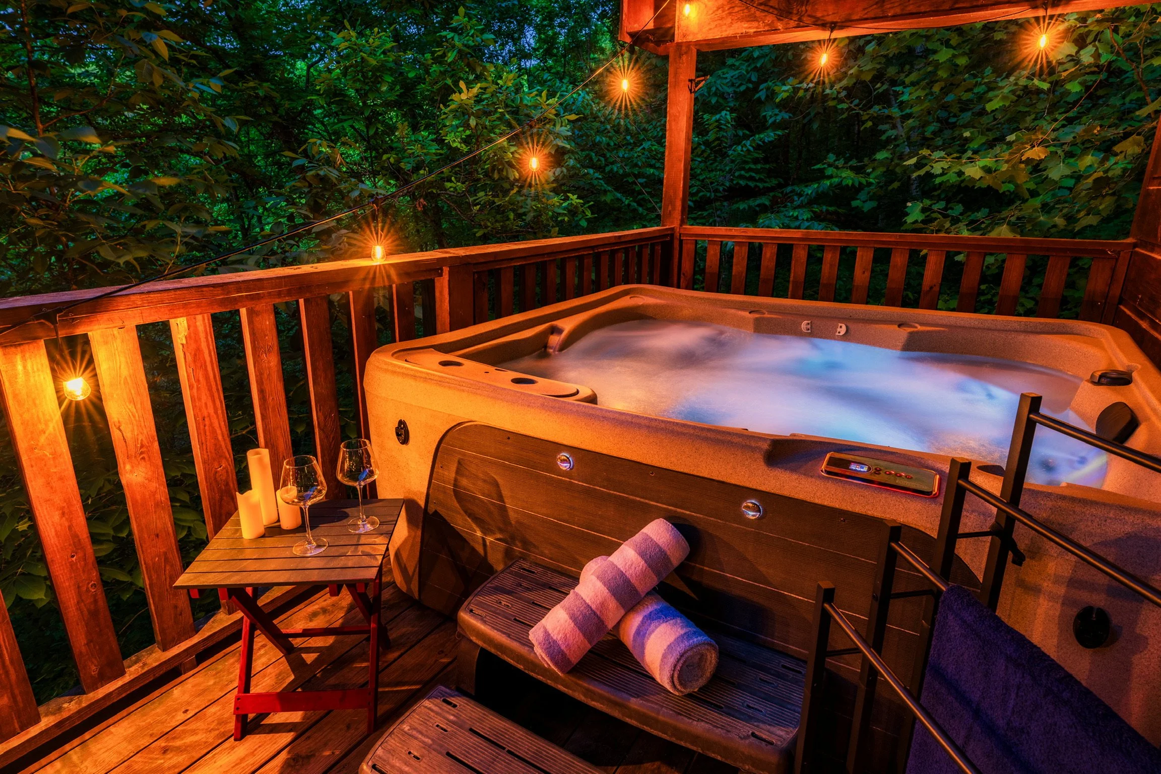 Blue Sage Hideaway Sevierville TN cabin — hot tub on covered deck with string lights and mountain view