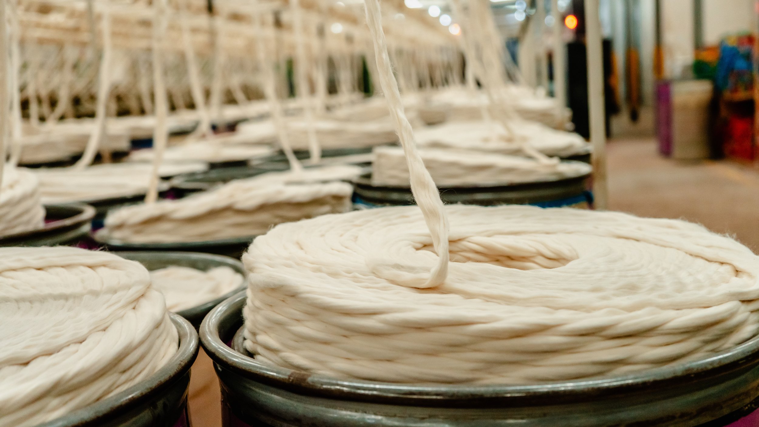 Coiled white rope stacked in small black buckets, with more buckets and shelves in the background.