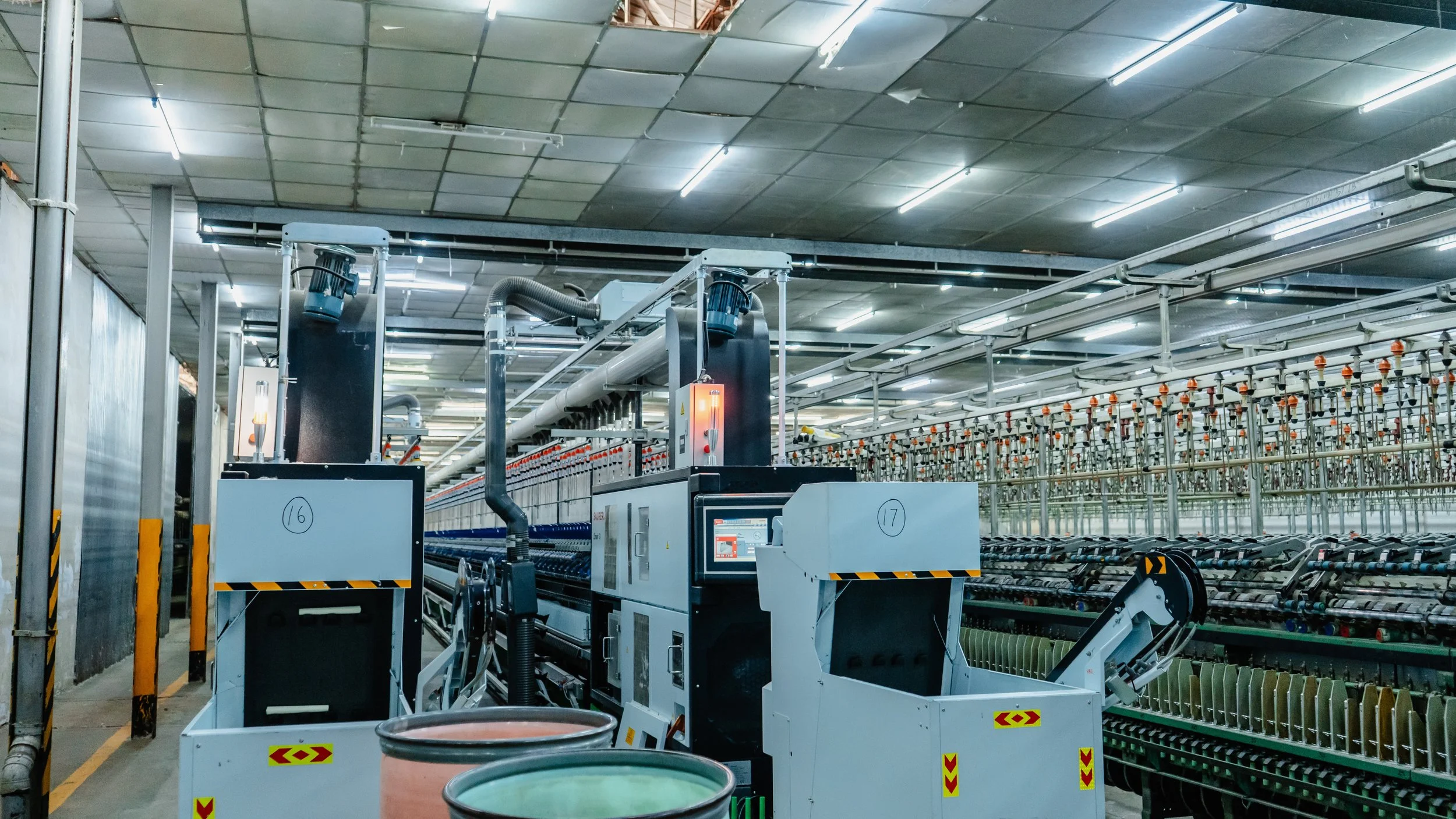 Industrial manufacturing facility with machinery, pipes, and conveyor system in a large warehouse or factory setting.