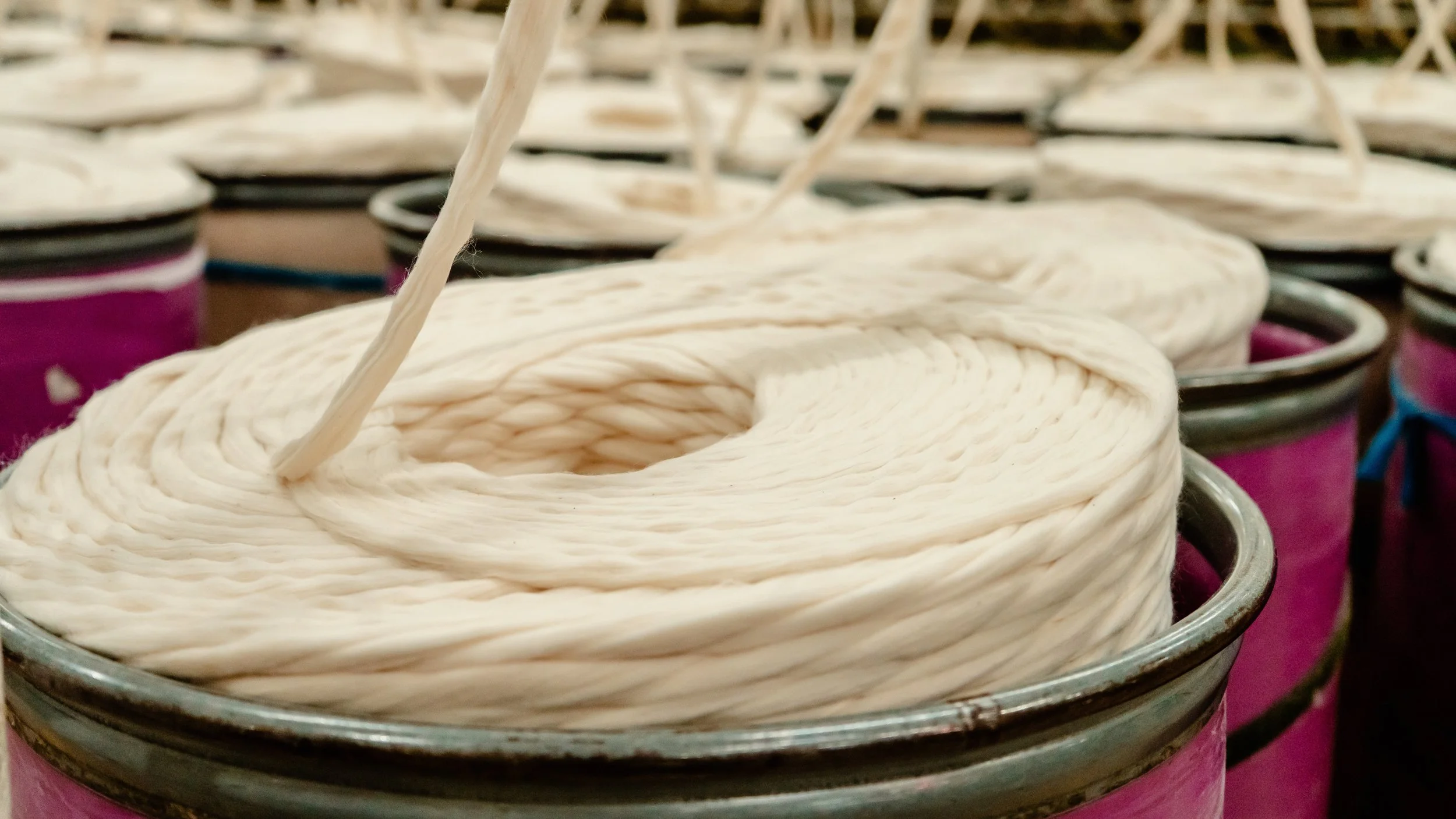 Close-up of several metal cans filled with tightly wound white twine, with some cans in the background showing more twine.