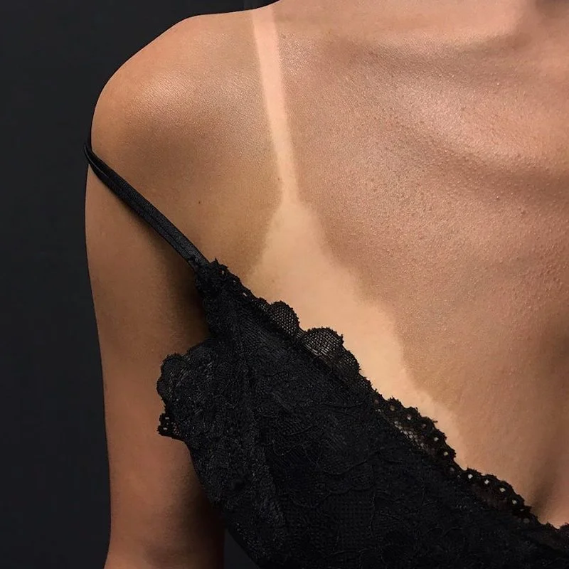 primo piano di una spalla nuda con una camicetta nera in pizzo che scivola lungo la pelle