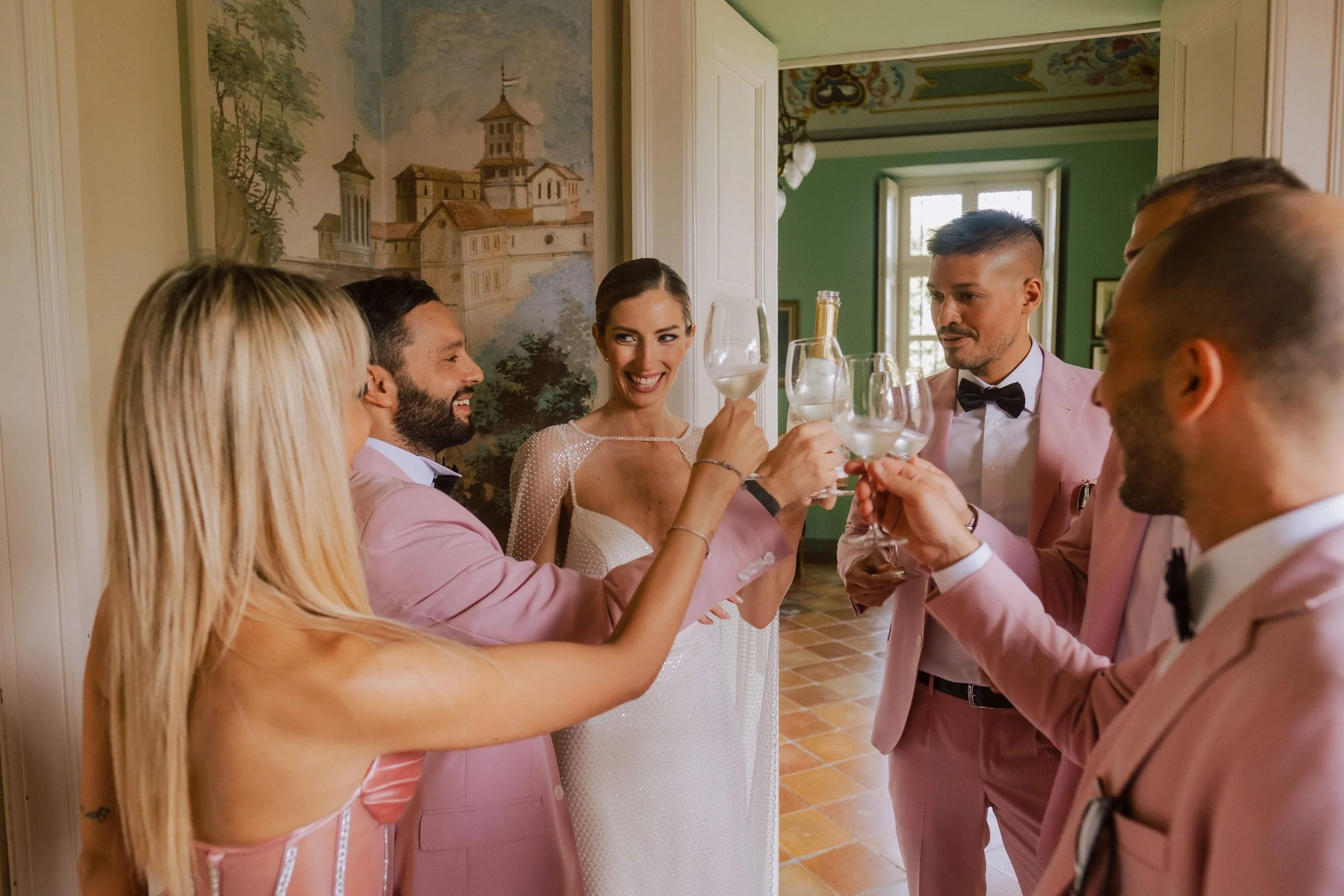 Un gruppo di persone al matrimonio con abiti eleganti che brindano con calici di vino o champagne.