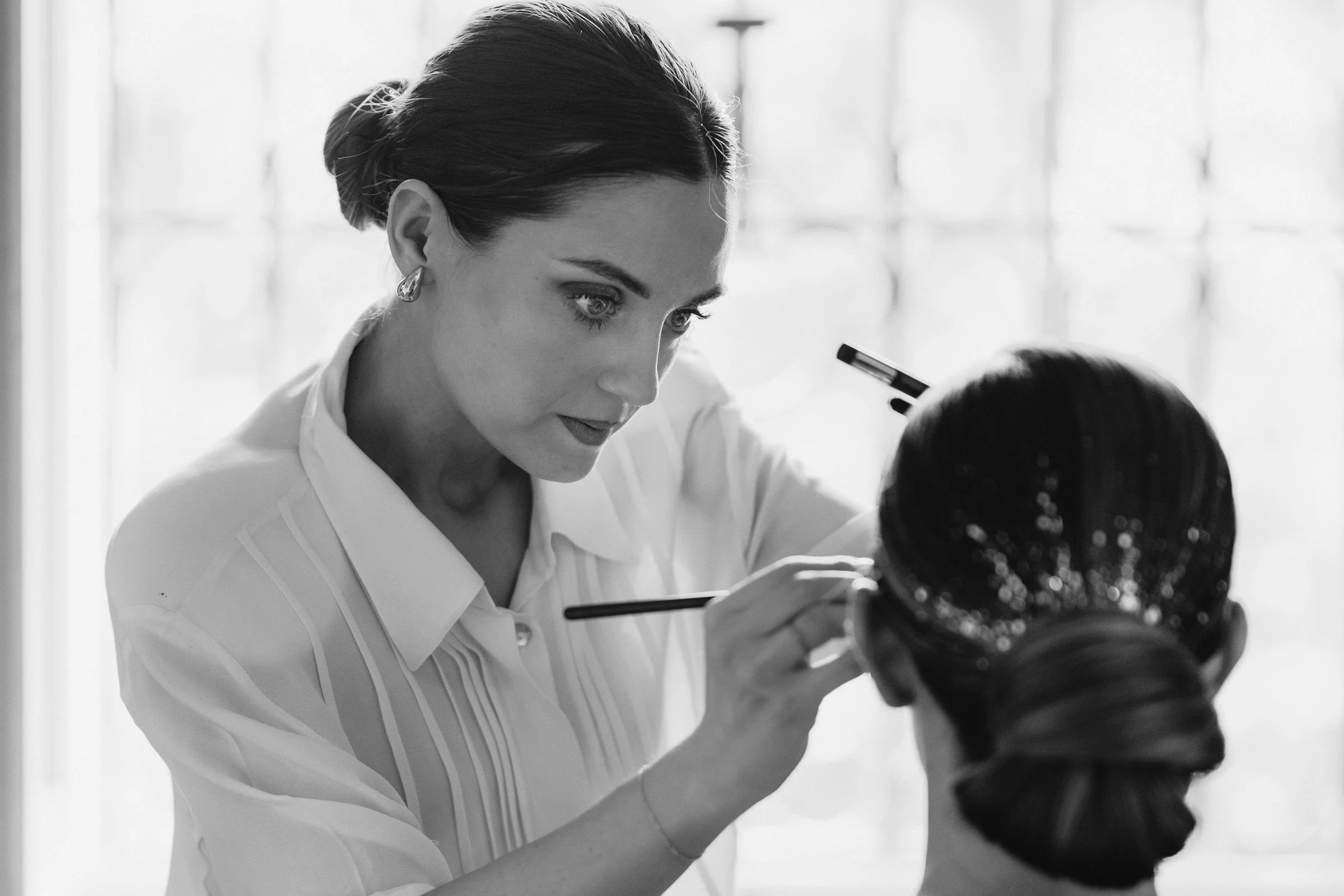 Una donna con capelli raccolti che si prende cura di un bambino, disegnando o facendo un trucco, in un ambiente con luce naturale.