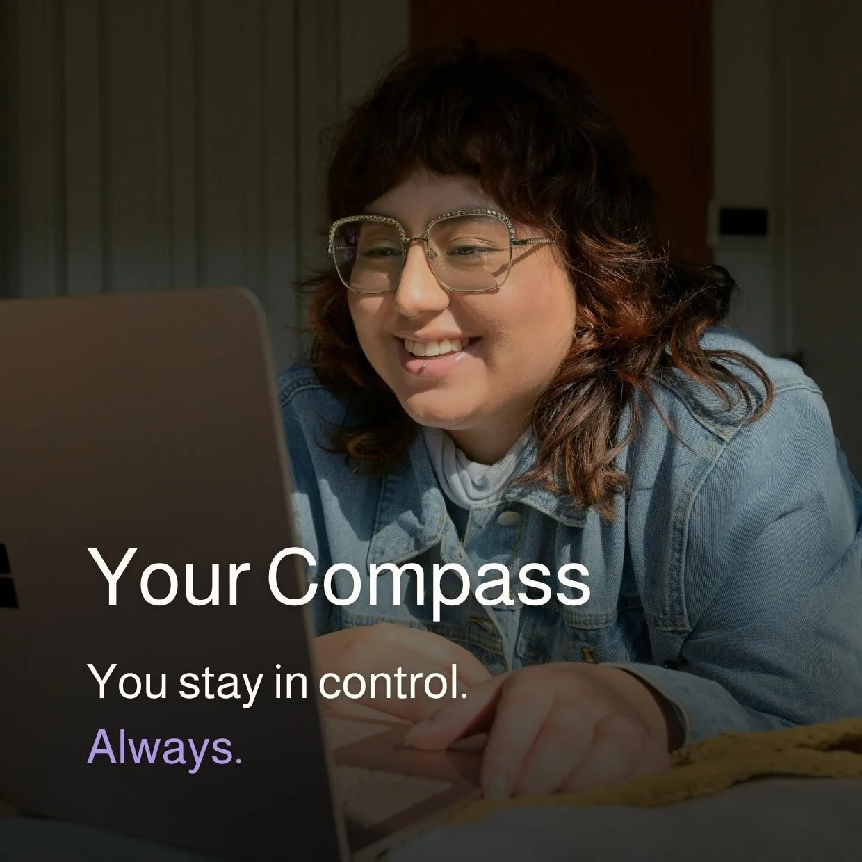 A woman with curly hair and glasses smiling at a laptop with the text 'Your Compass. You stay in control. Always.' overlaid.