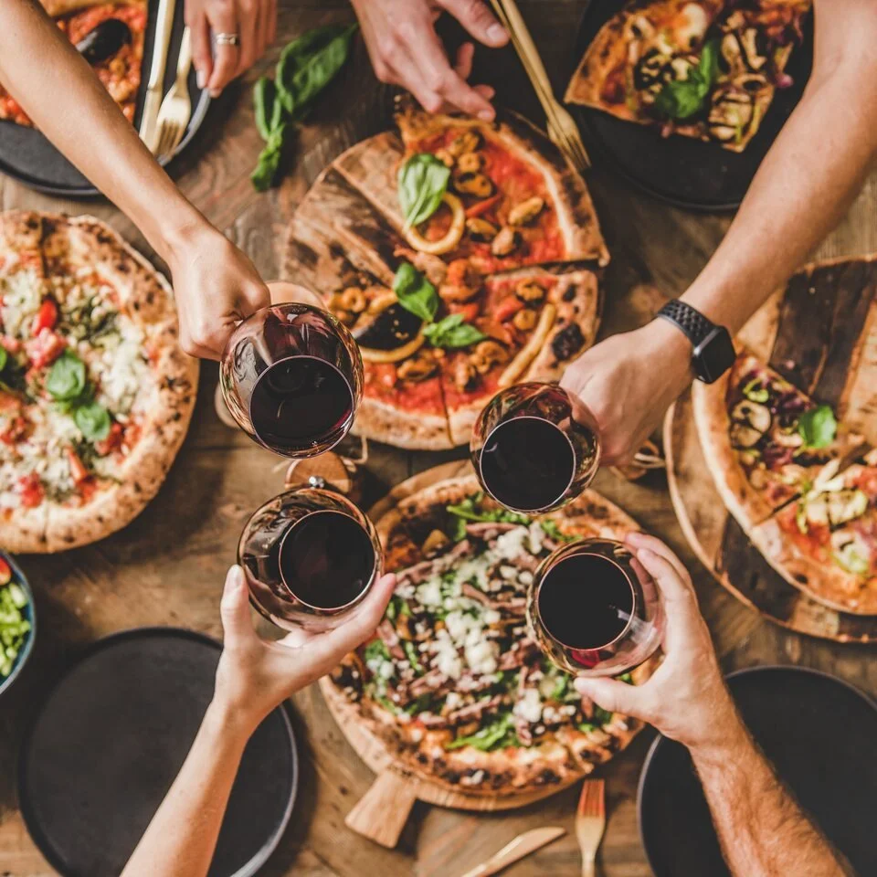 Pizza and wine shared around a table