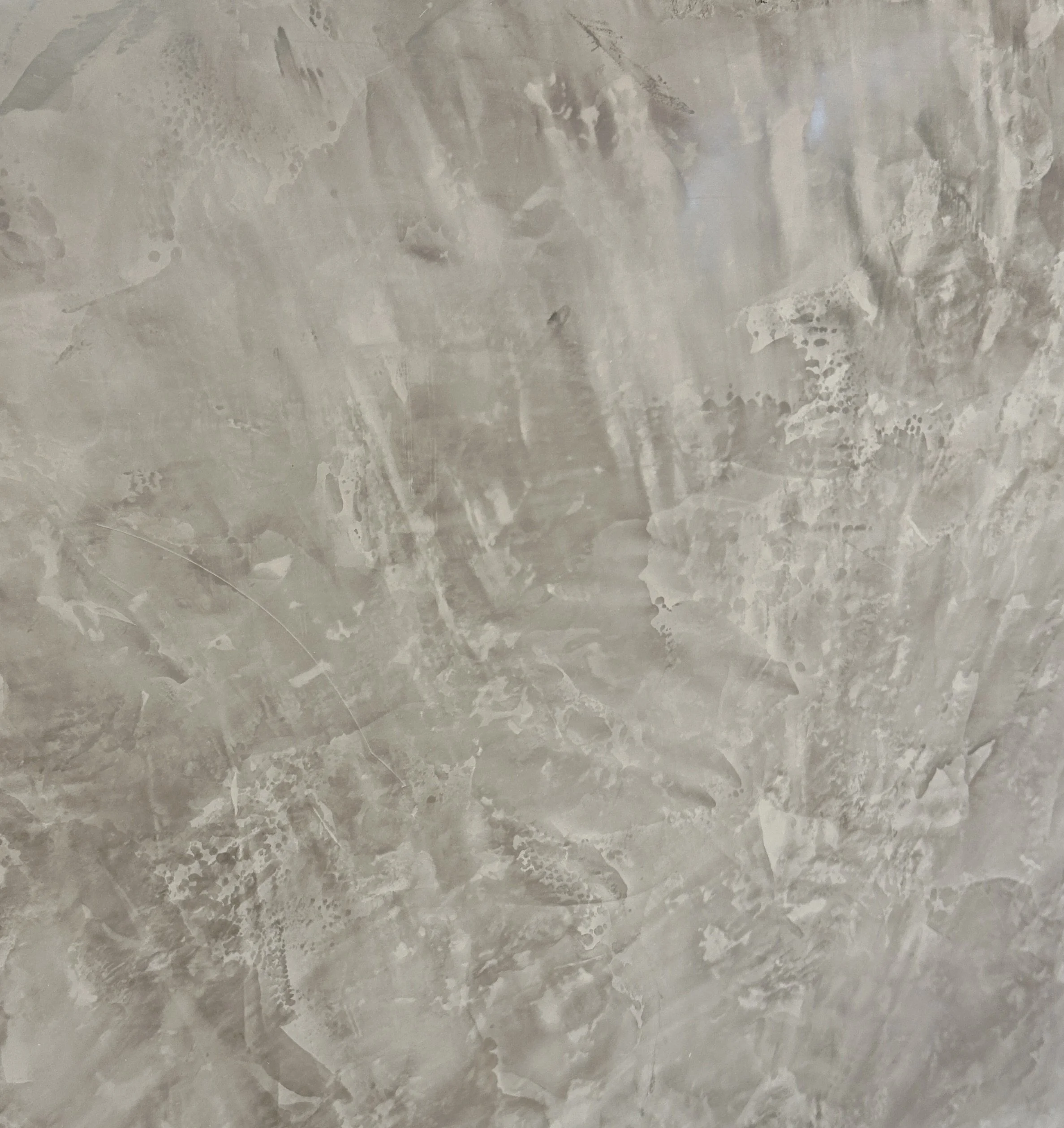 Close-up view of a marble or granite surface with a polished finish, showing natural veining and patterns in shades of gray and white.